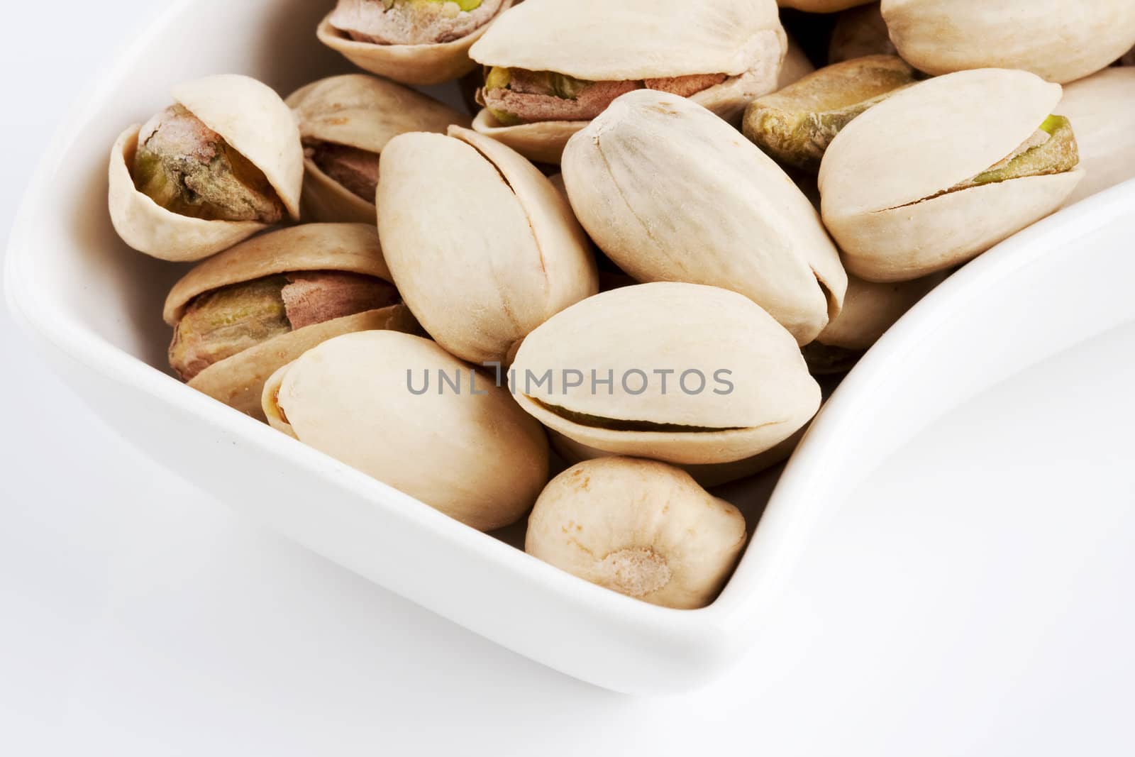 Close-up roasted and salted pistachios on white plate