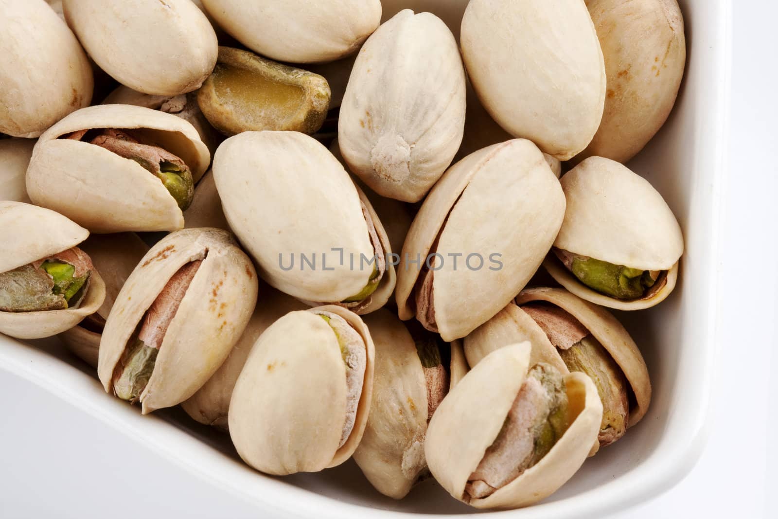 Close-up roasted and salted pistachios on white plate