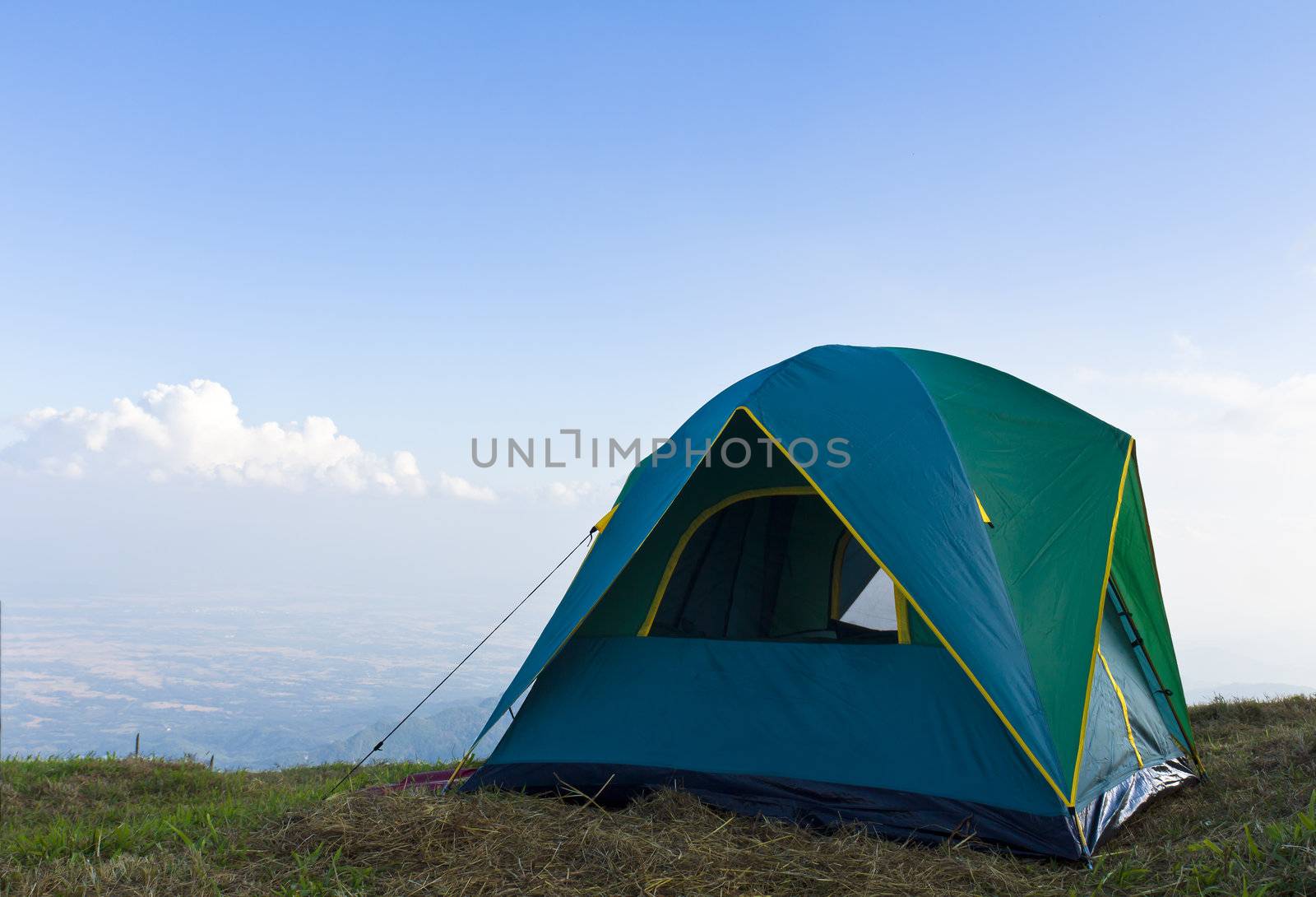 Tent on a grass under white clouds and blue sky