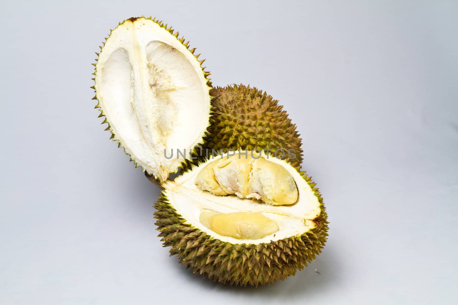opened durian with one unopened durian on whitish surface