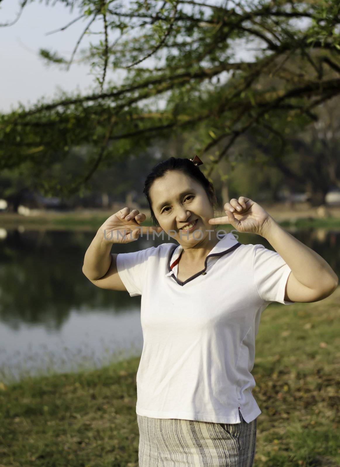 Happy asian woman posing against a background of trees in park