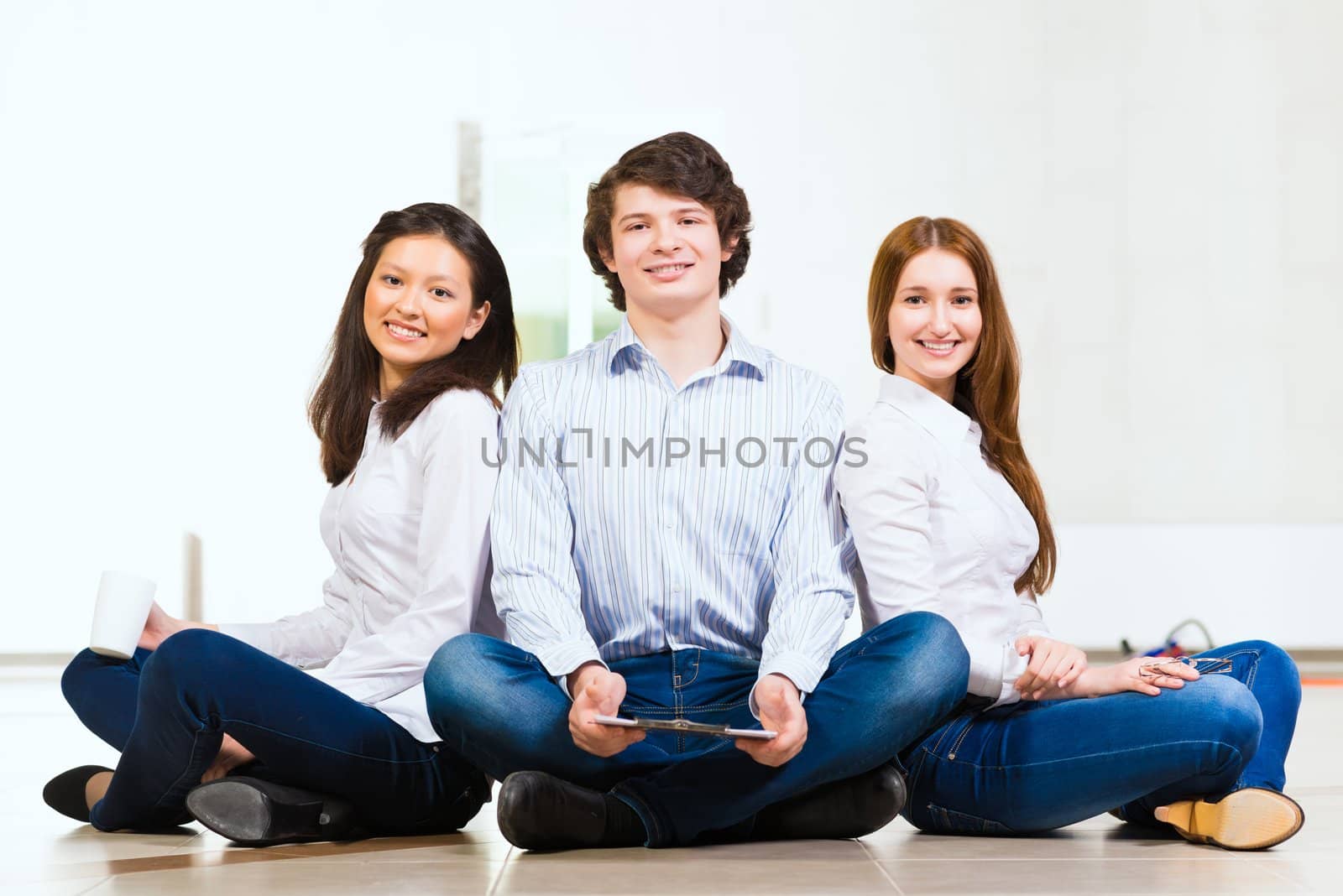 portrait of a group of young people sitting on the floor, man and two attractive women