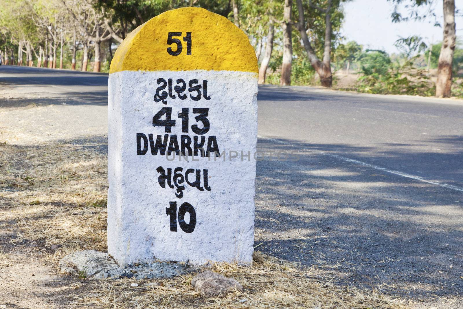 Rural landscape in Gujarat India incorporating 413 kilometers to Dwarka milestone and land mark on the coastal road to Dwarka and religious town for Hindus