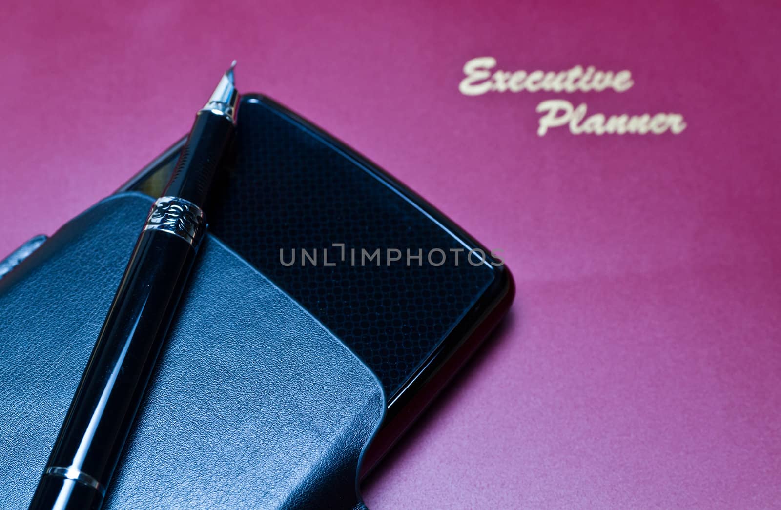 Brown executive planner with portable harddisk and pen seen under flash white balance