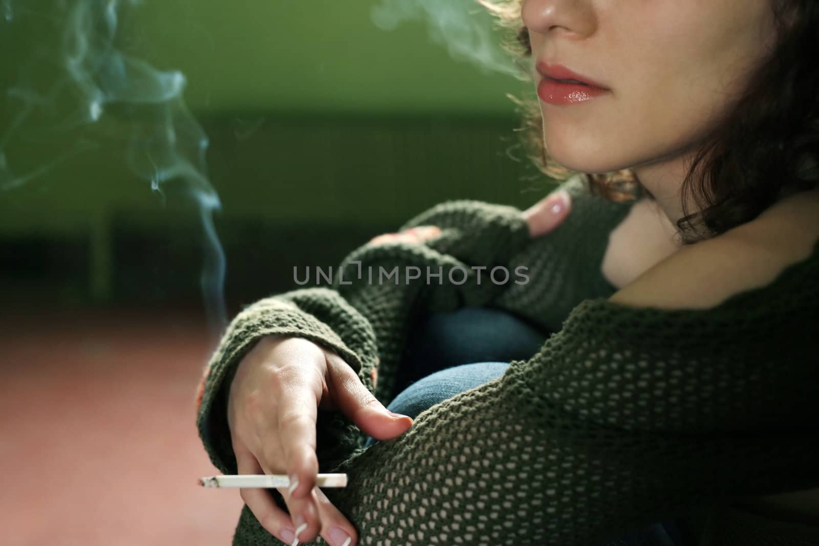 Portrait of the girl with a cigarette on a green background