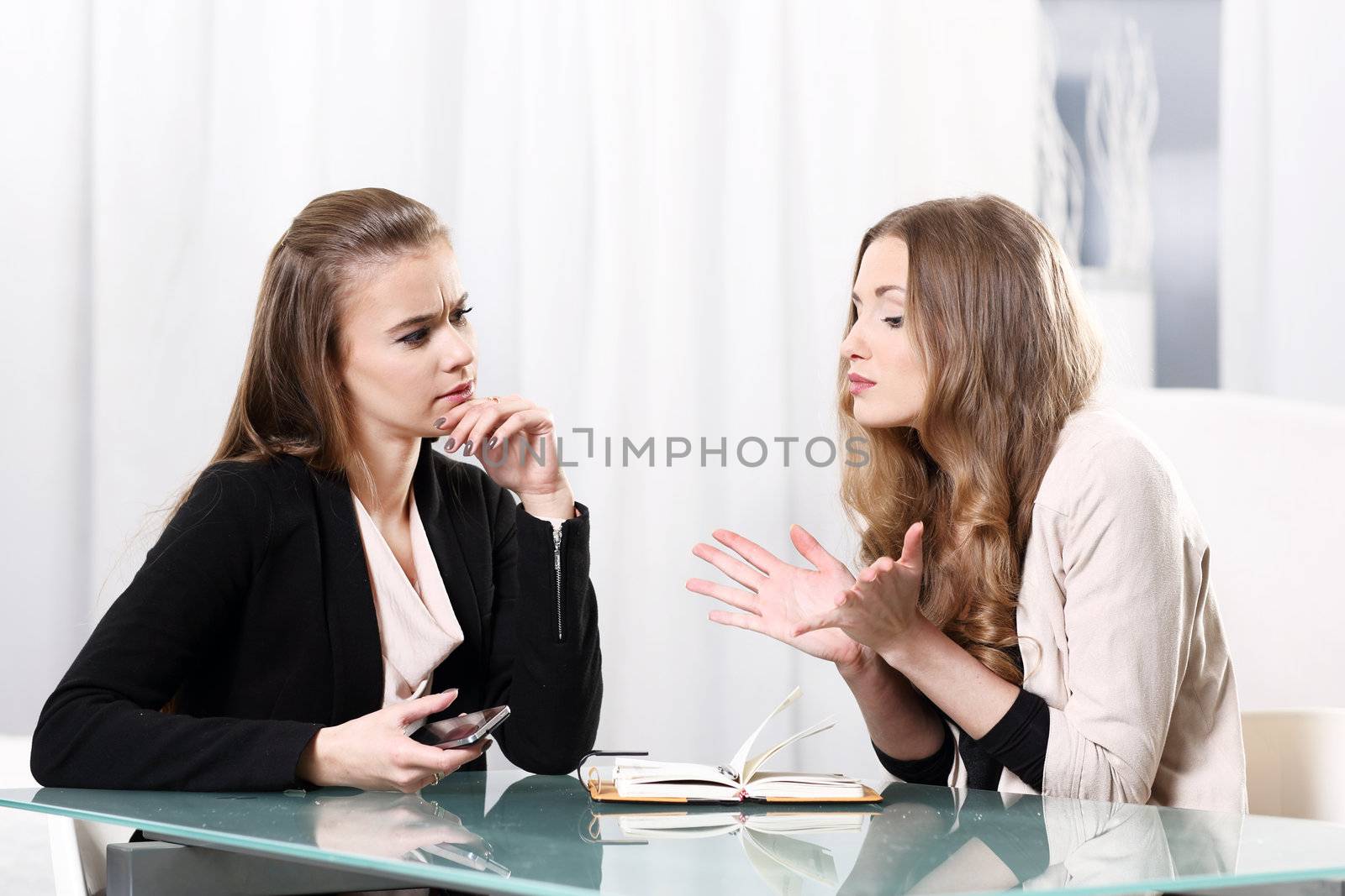 Two girls sitting at a glass table