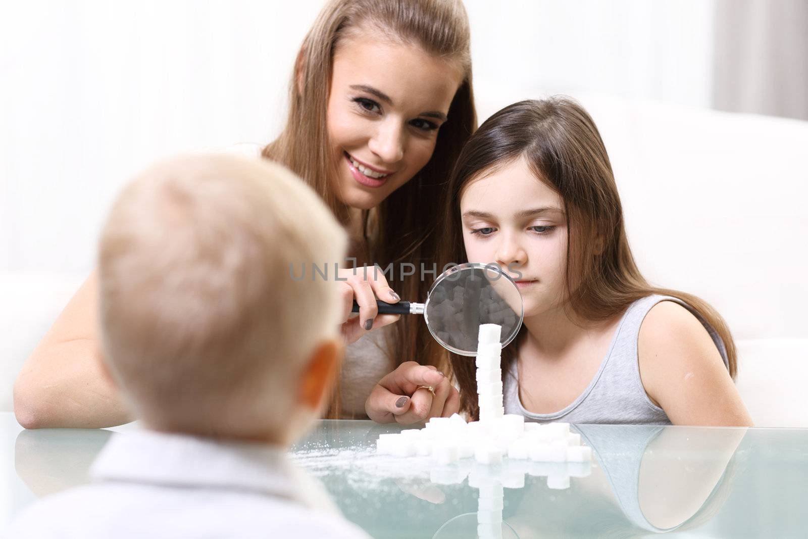 Woman with children looking through a magnifying glass at the table