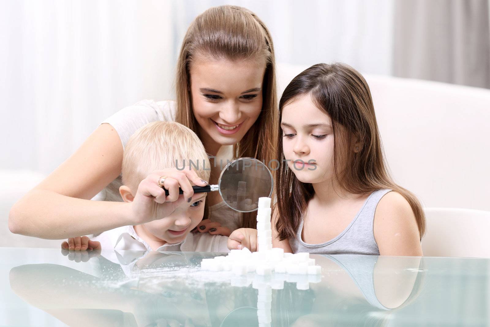 Woman with children looking through a magnifying glass at the table