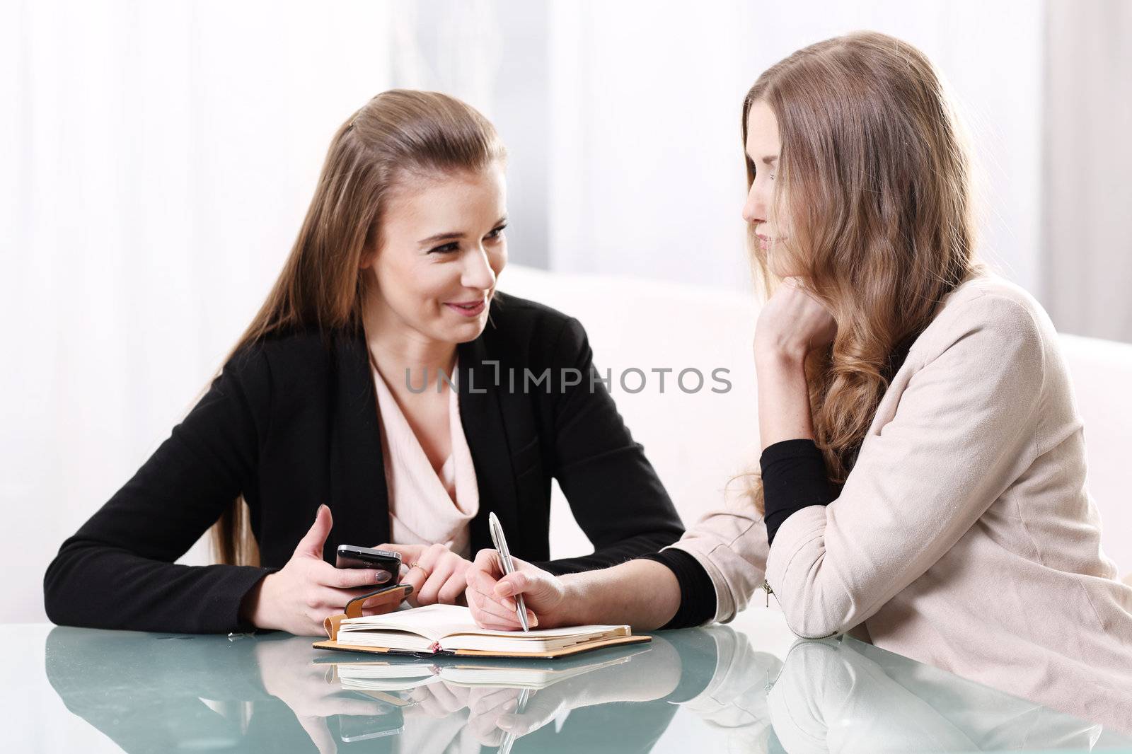 Two girls sitting at a glass table