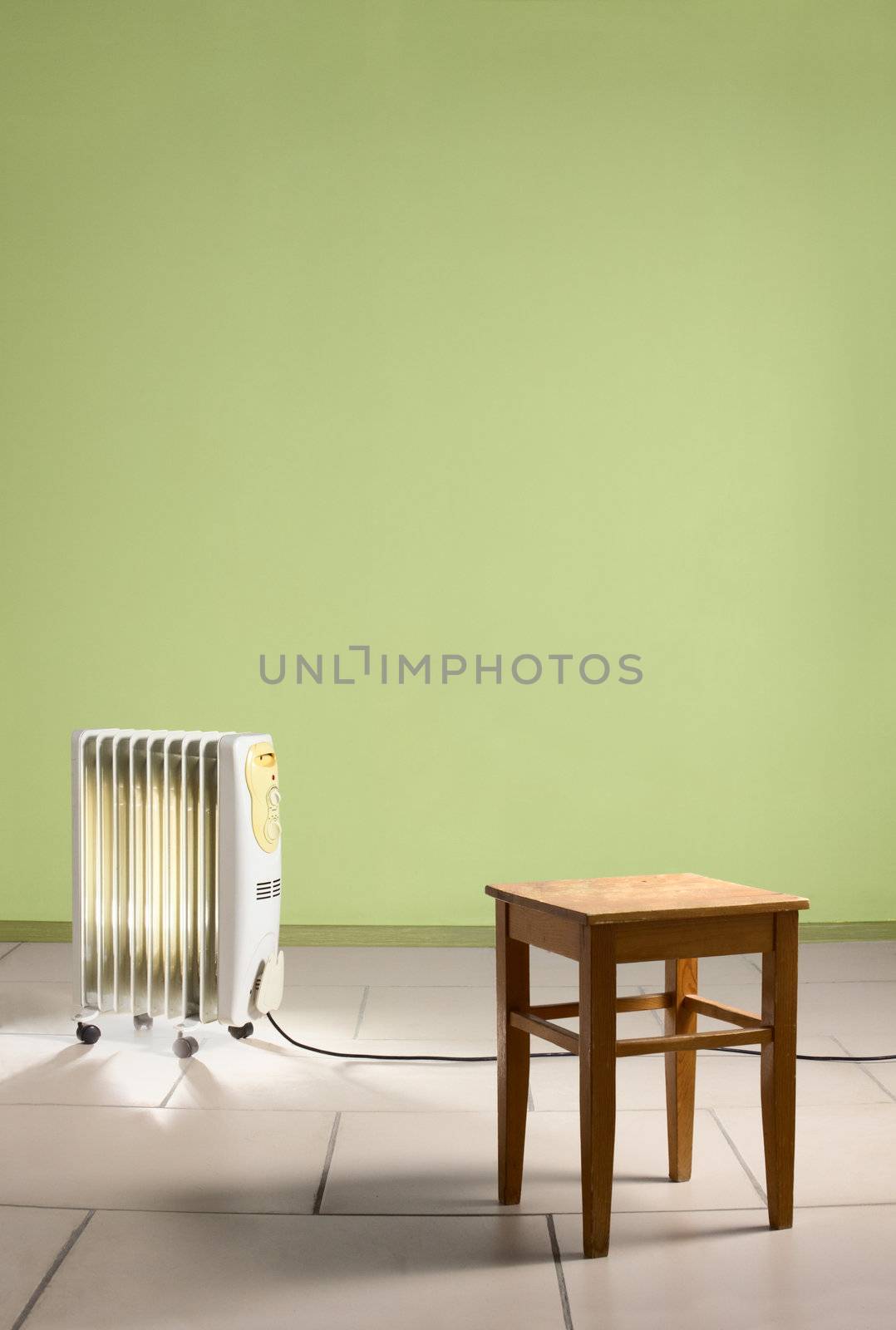 Empty room with heating electricity radiator and wooden chair. Green walls and stone tiles on the floor.