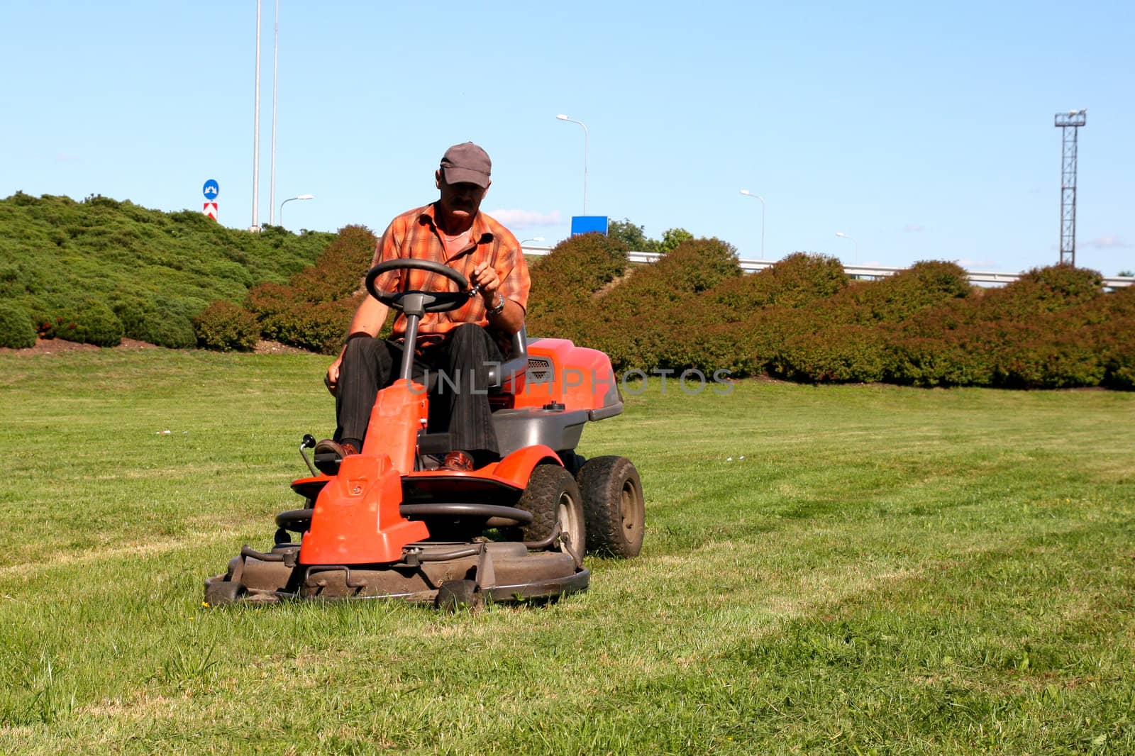 Mature man driving grass cutter in a sunny day
