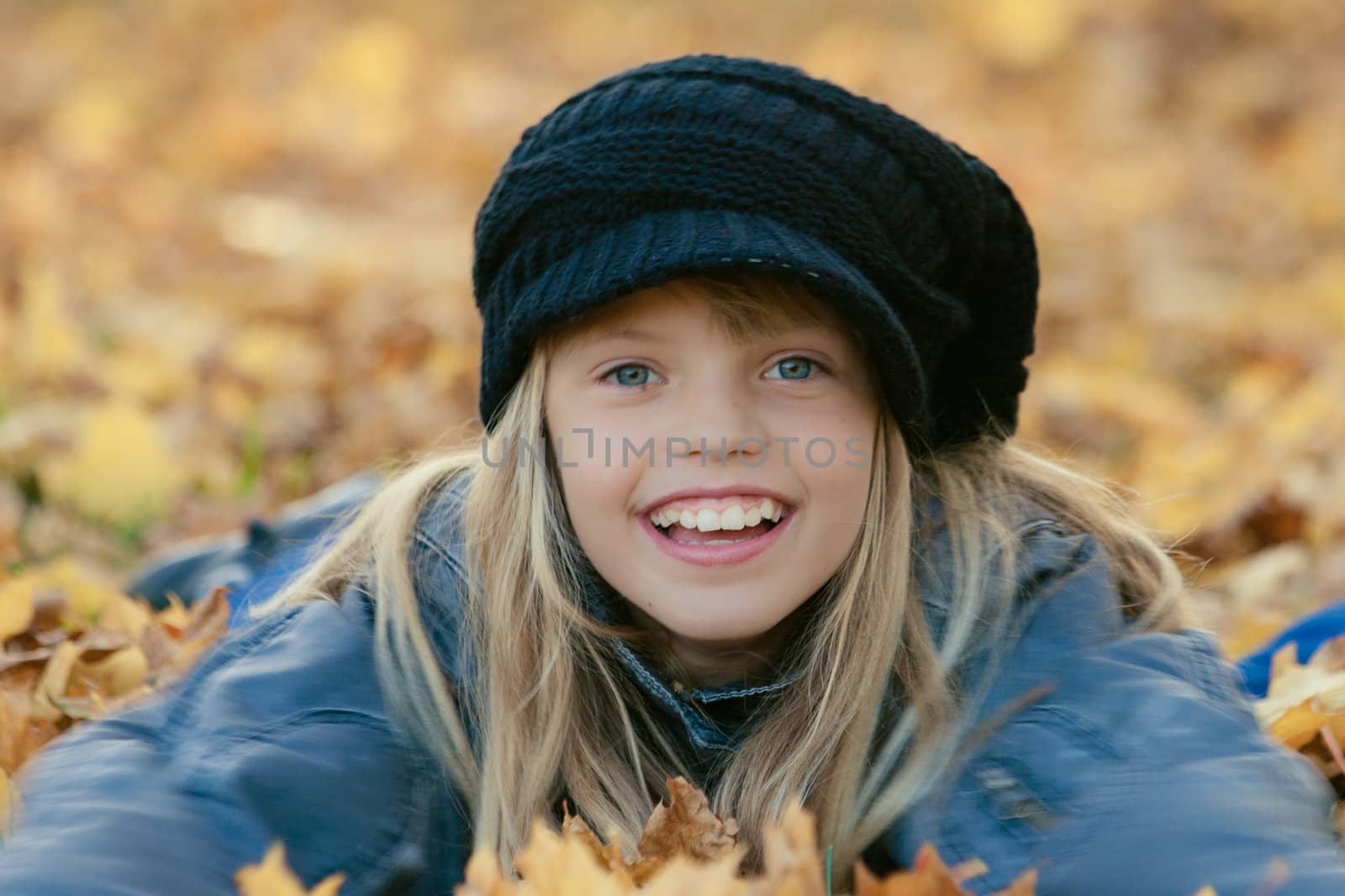 Little smiling girl  lying in fall leaves