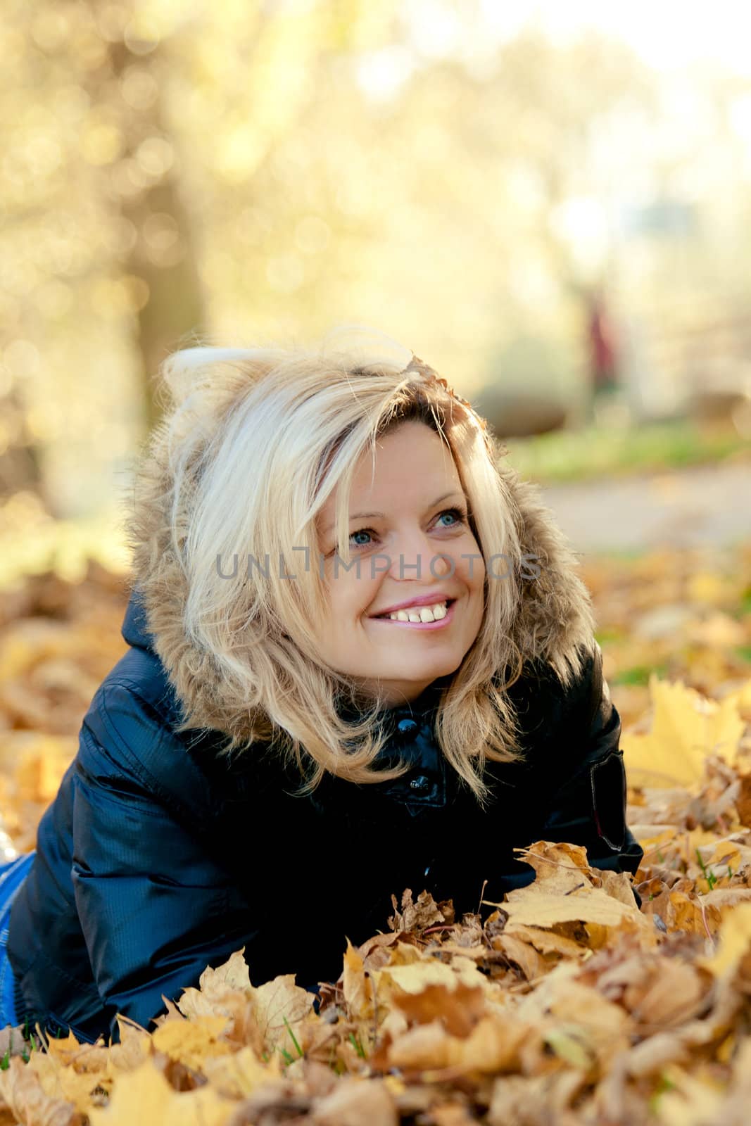 Smiling woman lying  on fall leaves