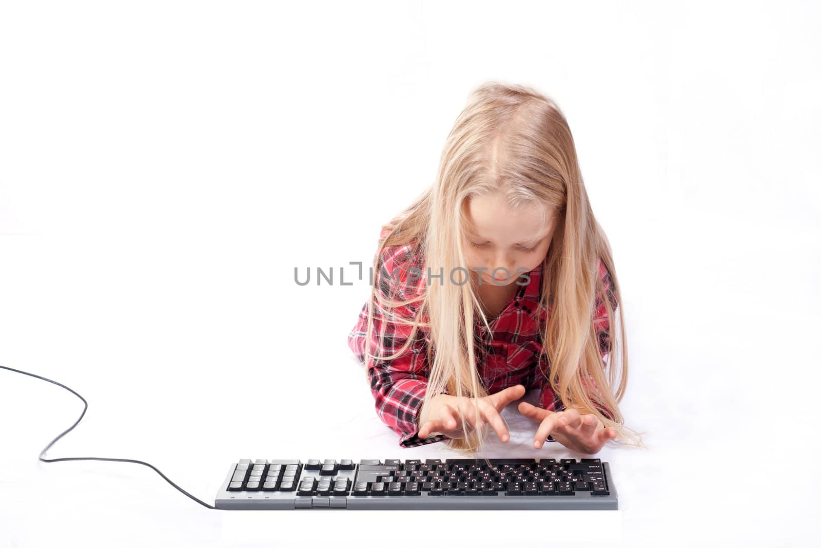 Little girl writes on a computer keyboard against white background