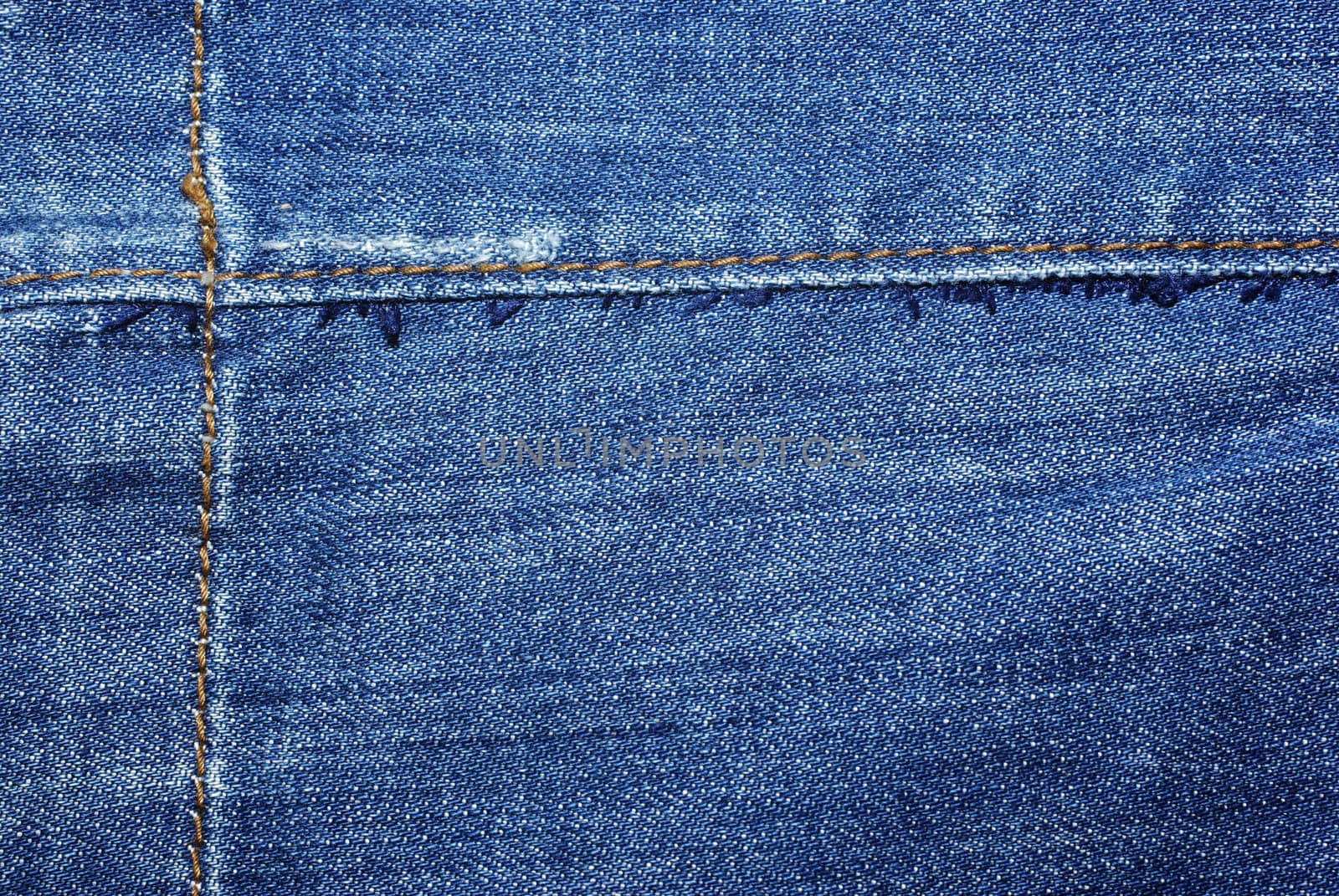 Blue jeans with yellow stitches abstract textile background.