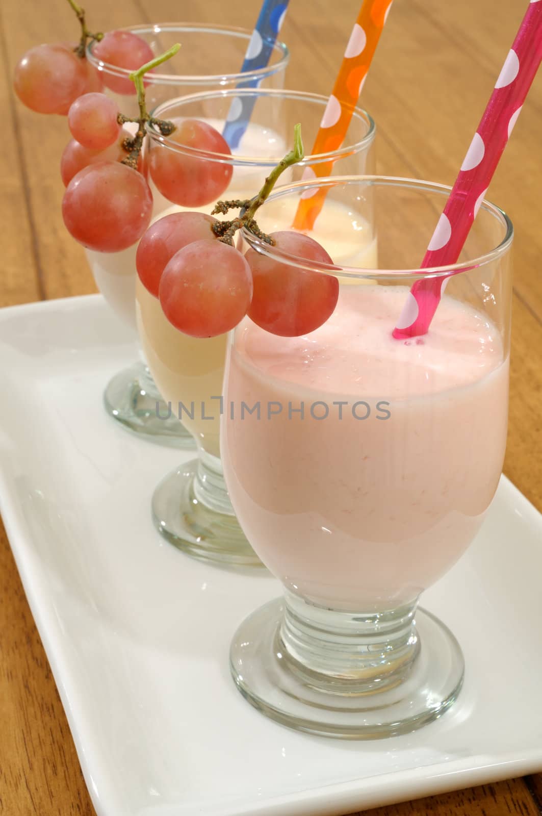 Smoothies with colored drinking straws decorated with grape