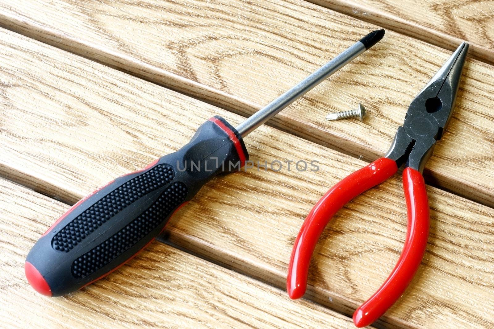 Screwdriver and Plier tools for handy do-it-yourself in a wooden tile background