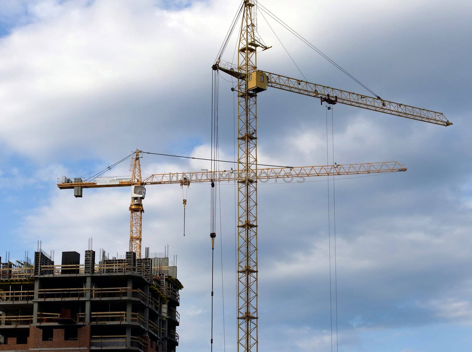 two cranes stand in front of a new building