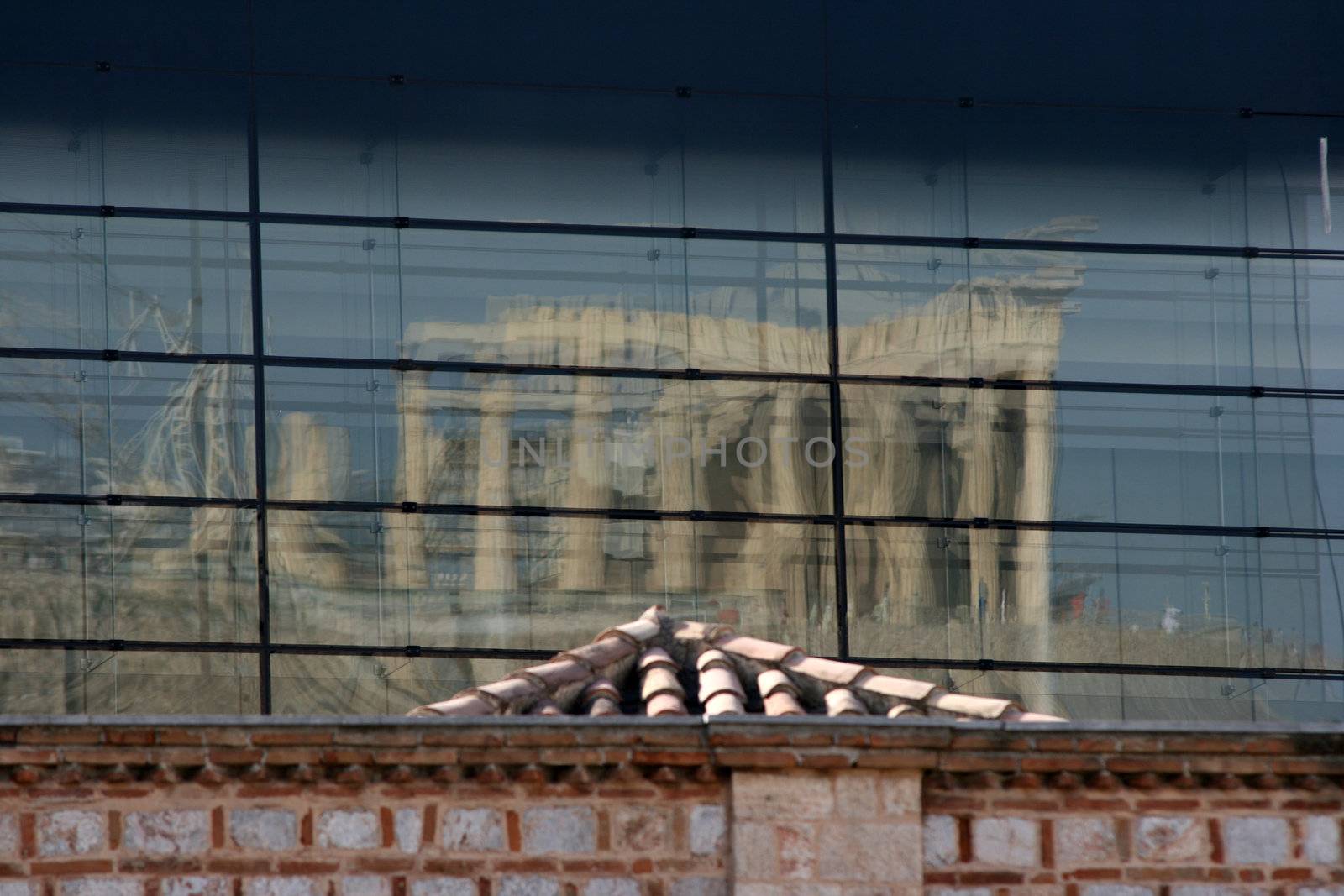 the reflection of parthenon on the glass wall of building 