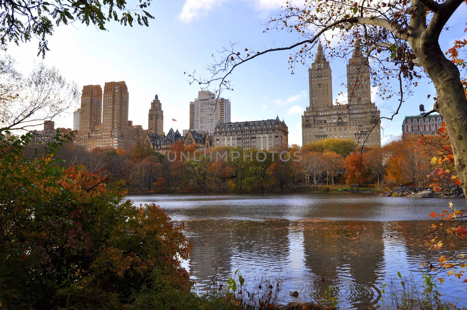 View over buildings in the upper west area of New York with the lake in central park in the foreground.