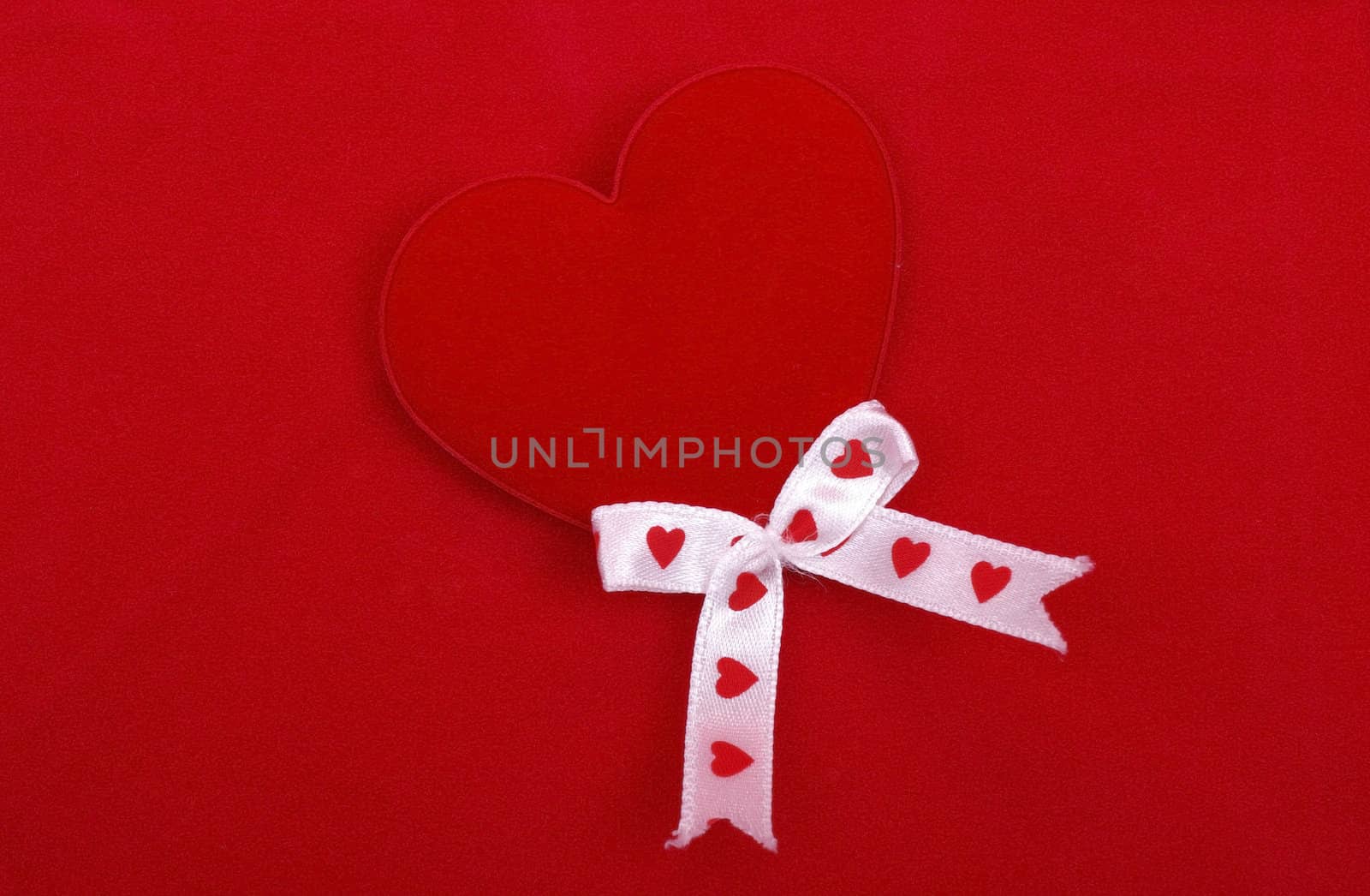 Red heart with silk ribbons isolated on red textured background. by borodaev