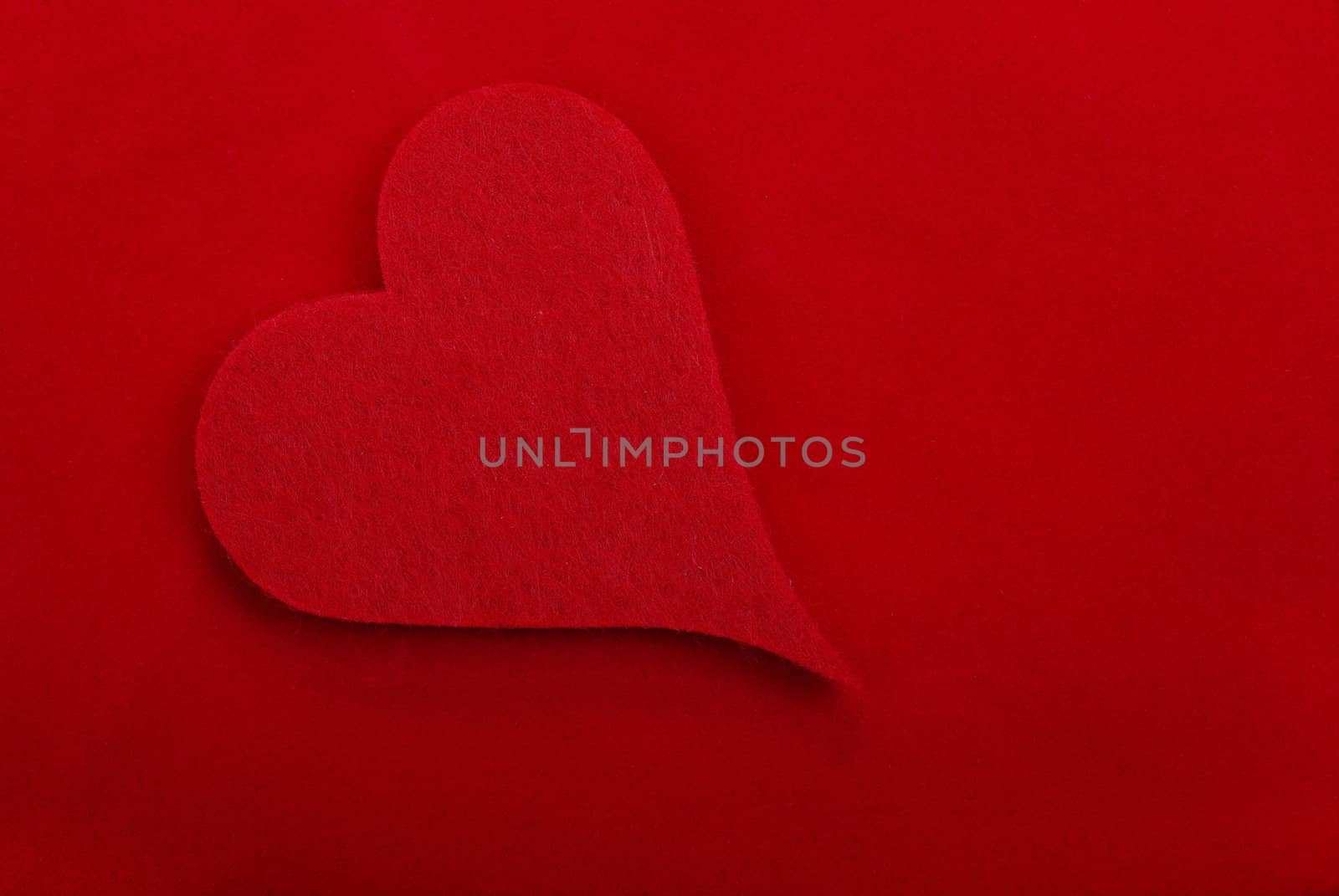 Red textile heart isolated on red background. Empty space for your design.