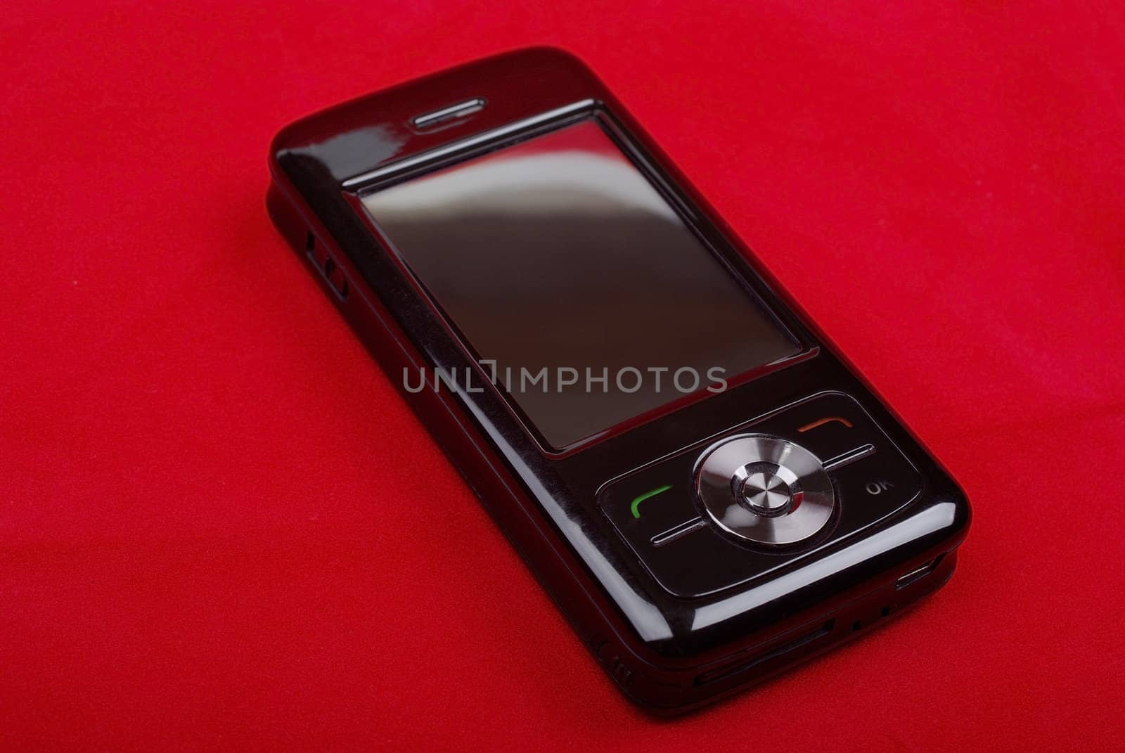 Shiny black PDA phone isolated on red background.