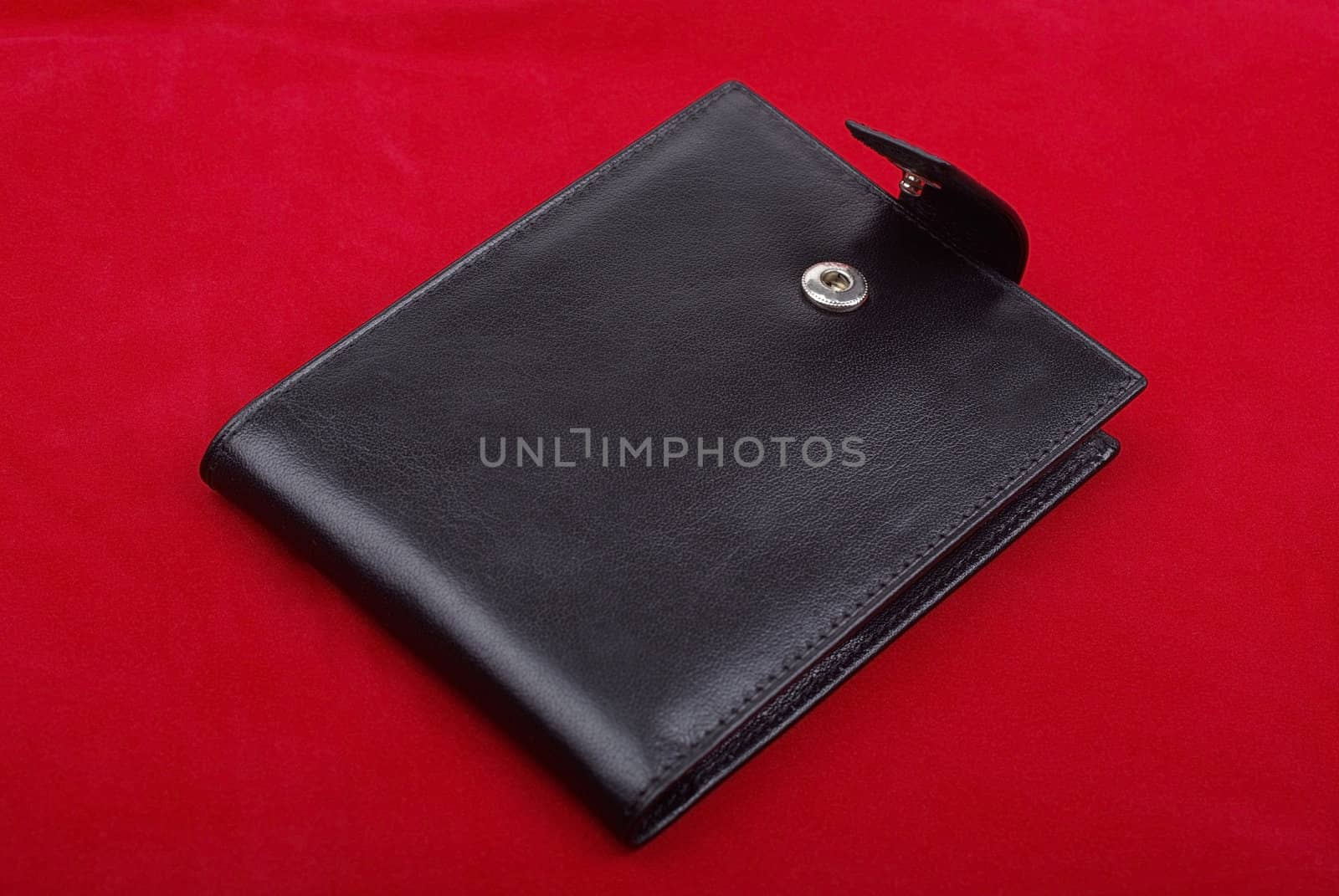 Black leather wallet isolated on the red background. Studio shot.