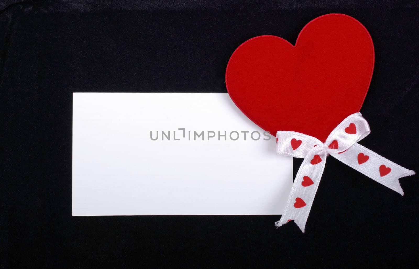 White card with red heart isolated on black velvet background. E by borodaev
