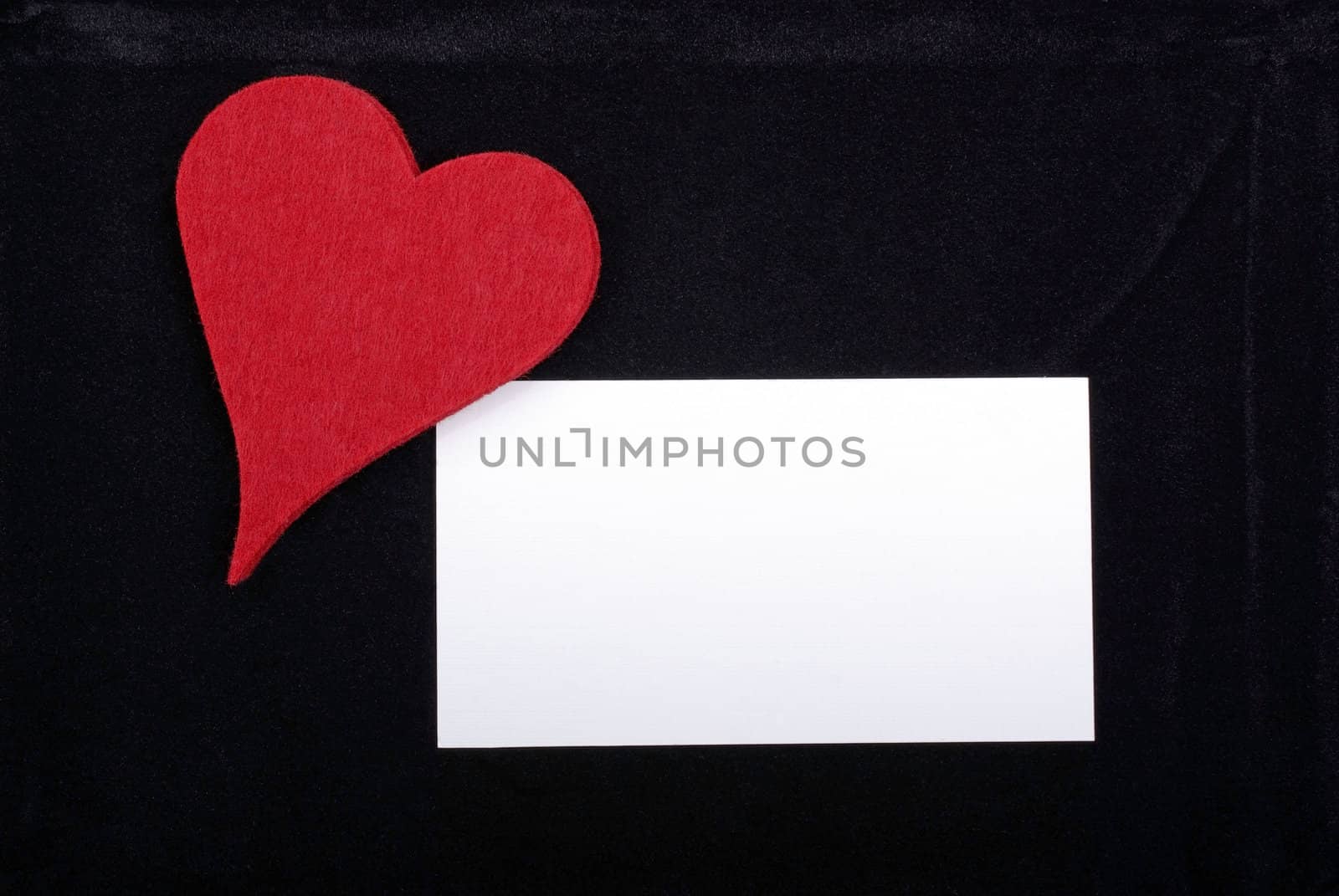 Red heart and empty card isolated on black velvet background. Empty space for your text or design.