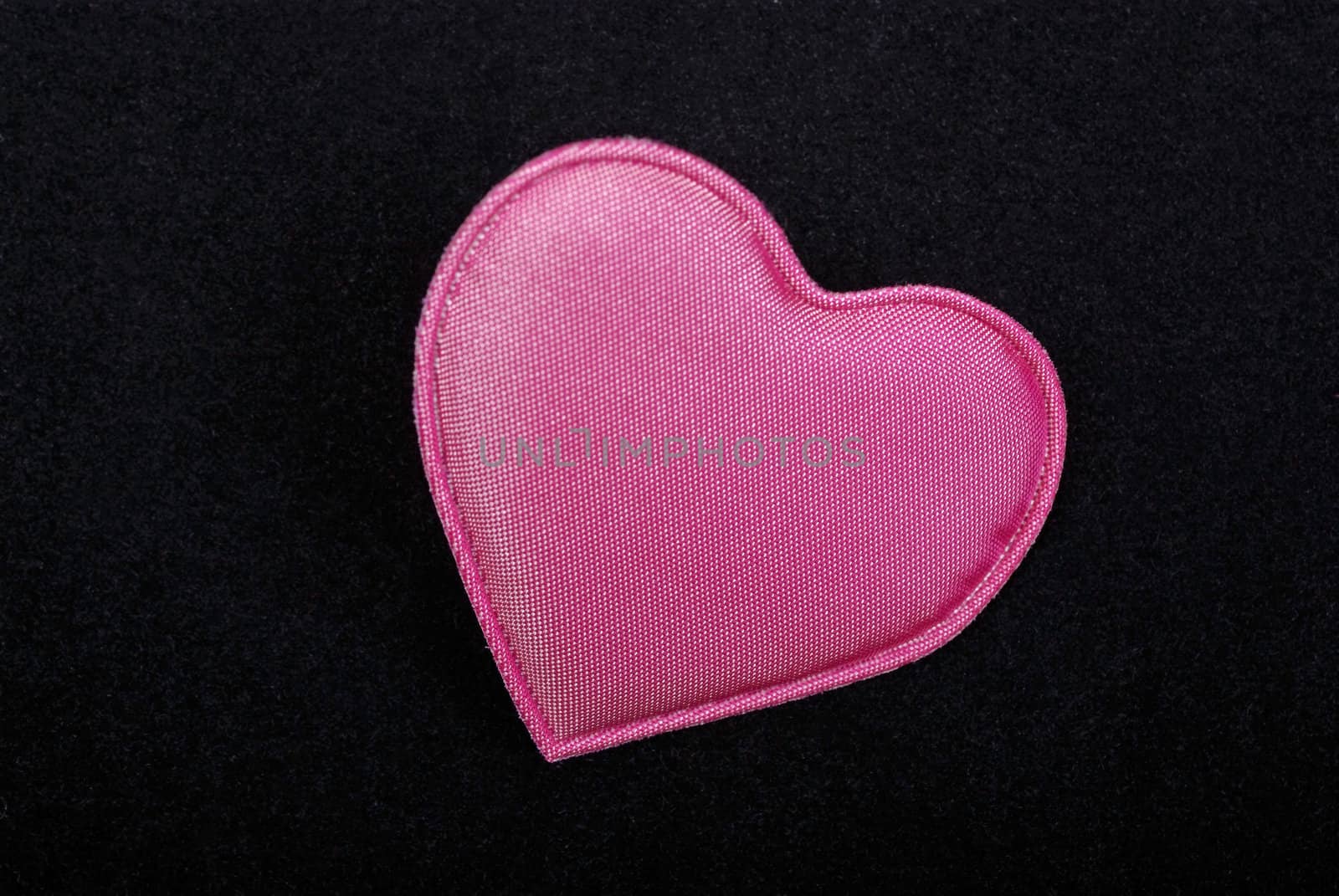 Pink heart macro isolated on black velvet background.