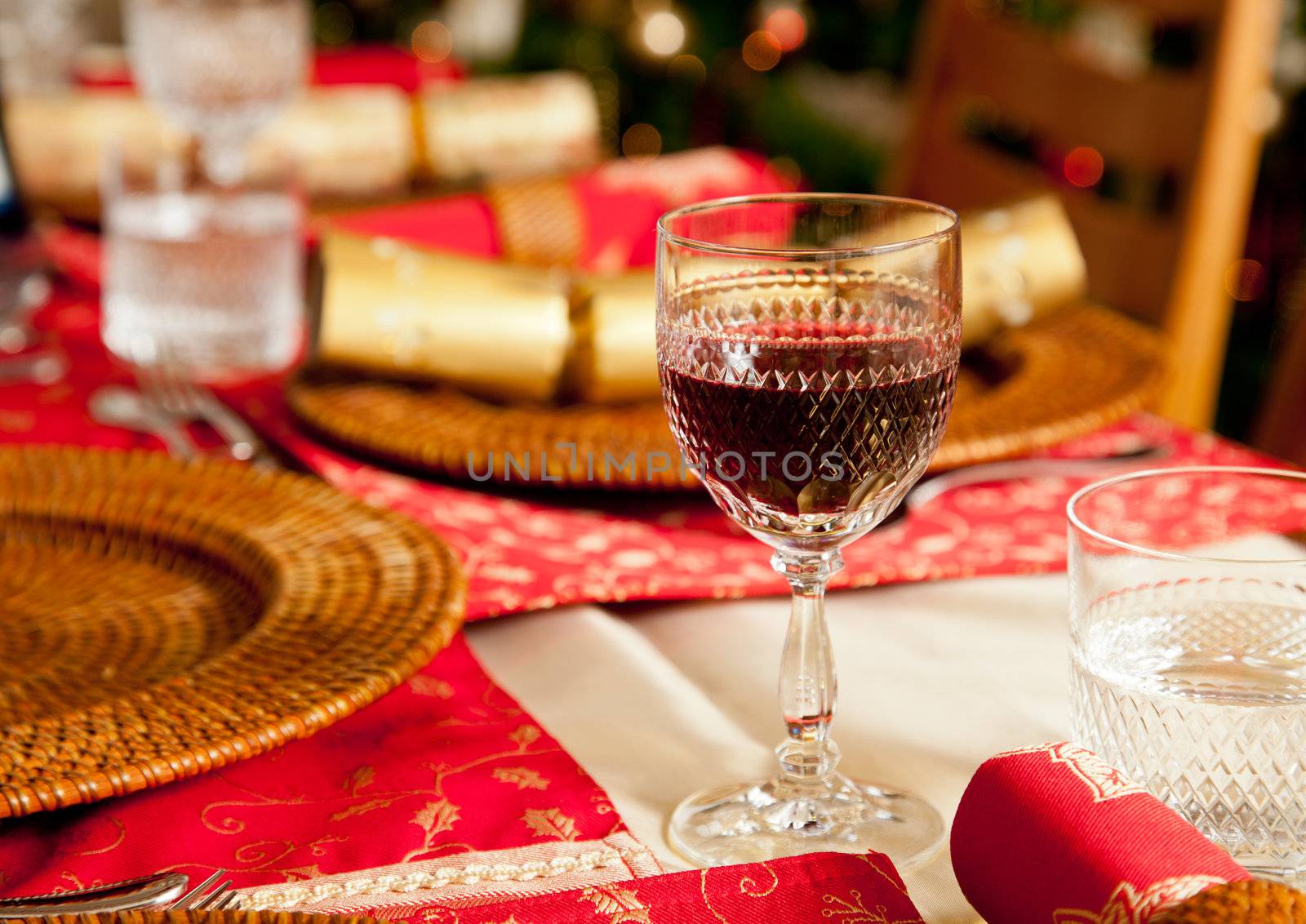 Christmas crackers on table set for Christmas lunch with candles and tree in background