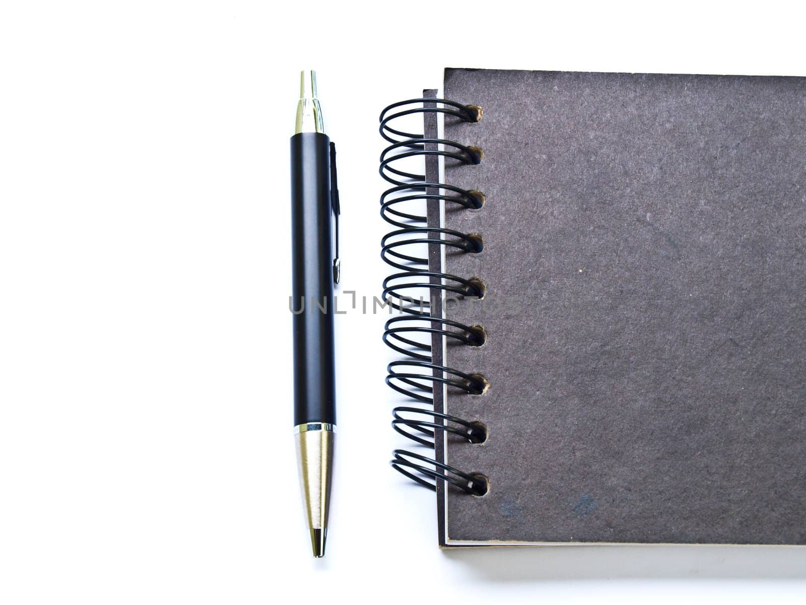 Ballpen and a black spiral binding notebook cover on white