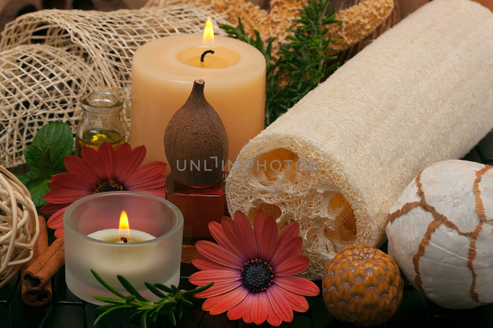 Spa concept with aromatic candles, herbs, beautiful daisies, massage oil and loofah