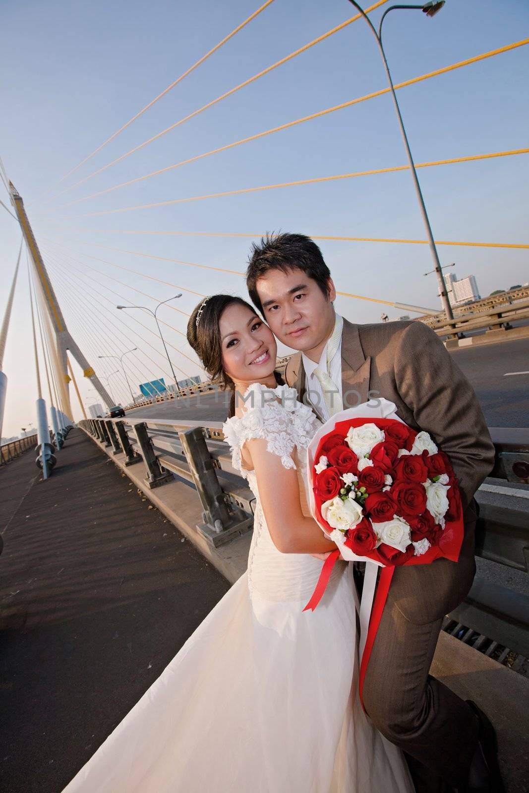 couples of happiness Bride and groom with beautiful rose bouquet on the road bridge