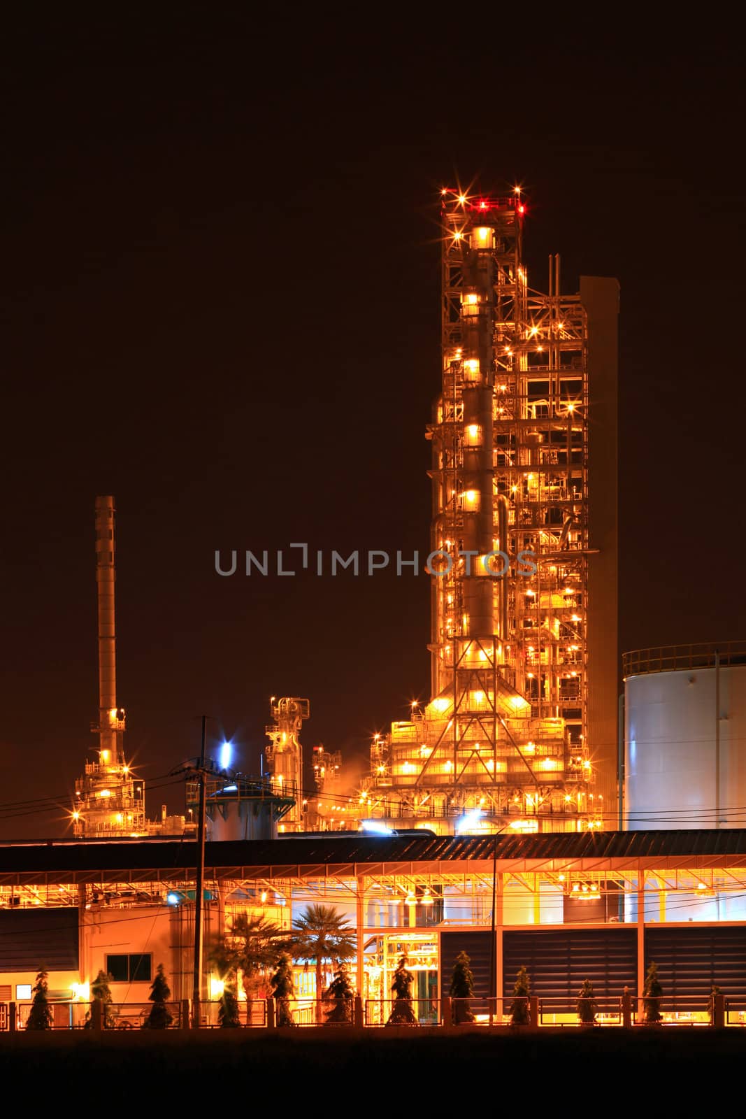 scenic of petrochemical oil refinery plant shines at night, vertical closeup