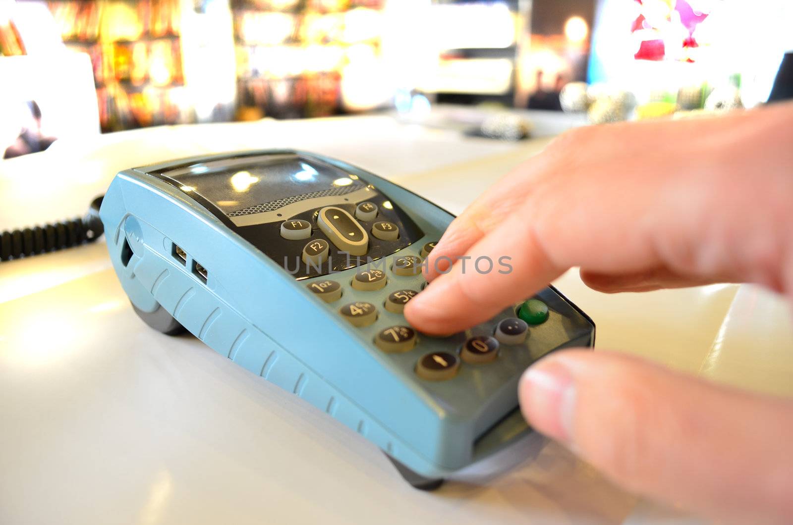 Closeup of hand typing payment details on POS machine in a store