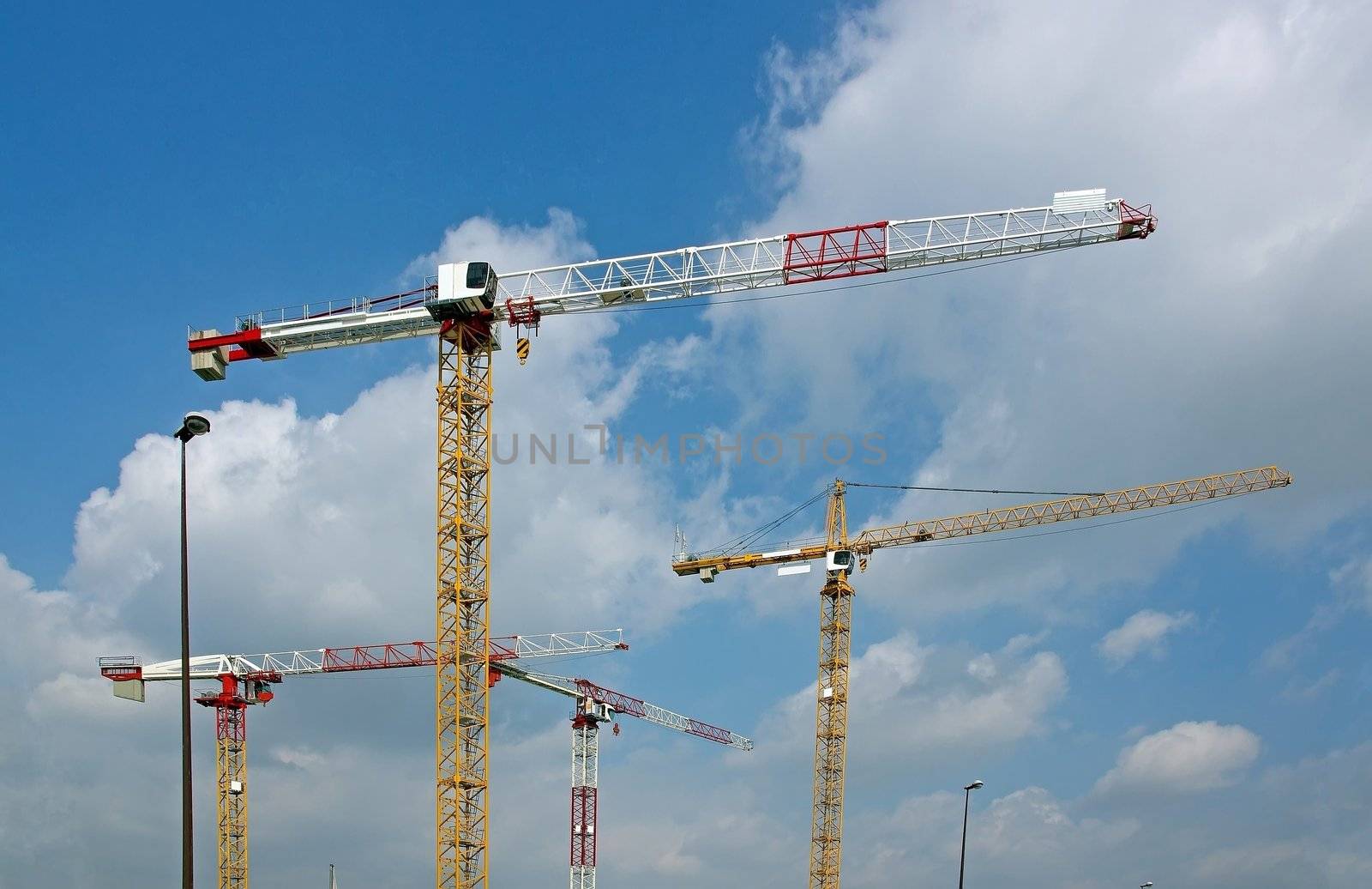 four cranes on a construction site and a few street lights