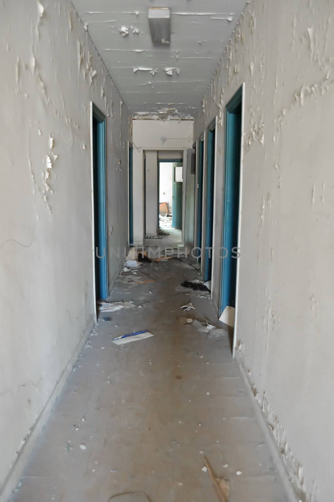 Long empty hallway and doors in abandoned building.