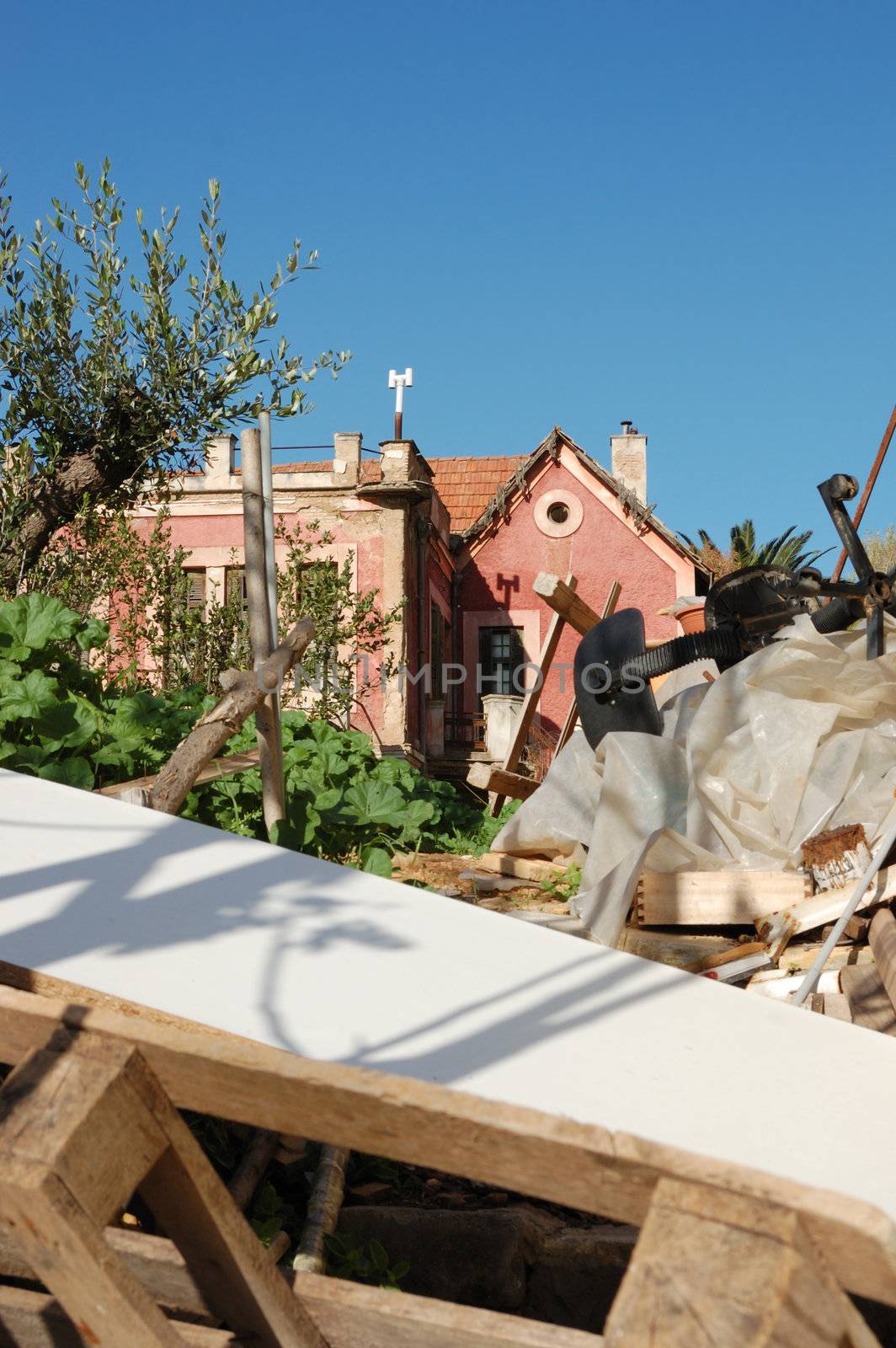 Pile of broken furniture and debris in the abandoned neoclassical house garden.