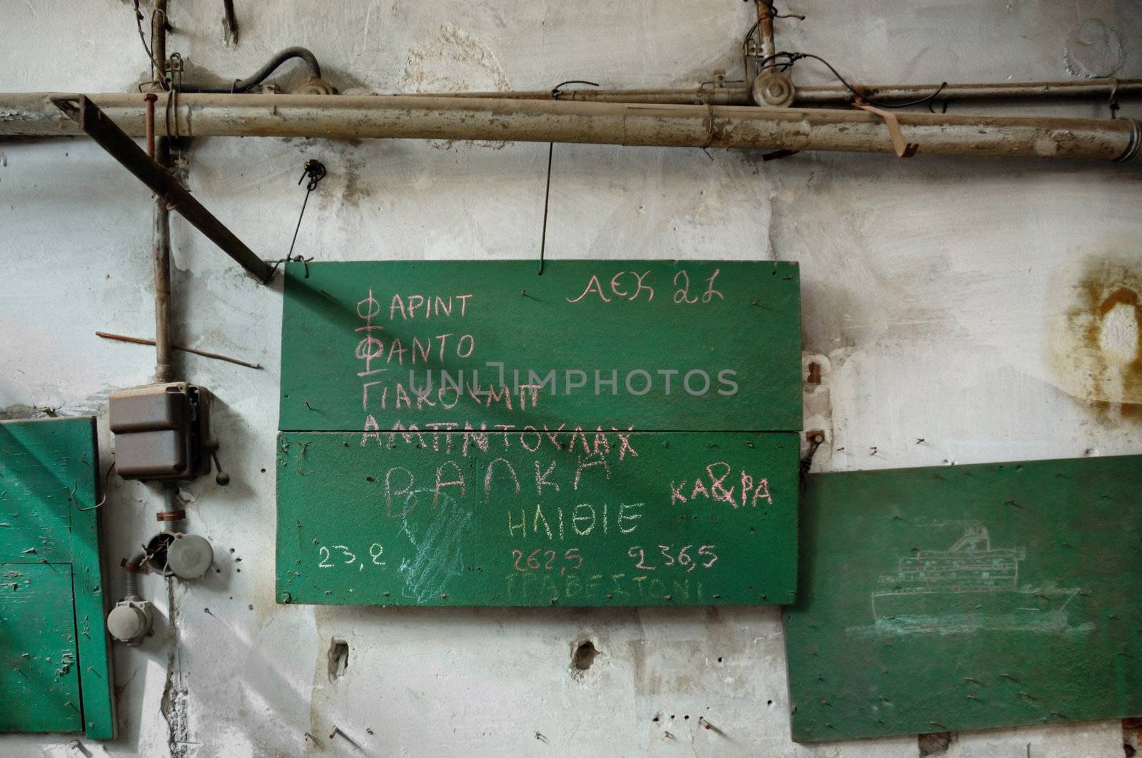 Sailing ship drawing in abandoned factory. First names and misspelled insults written in Greek by muslim immigrant children.