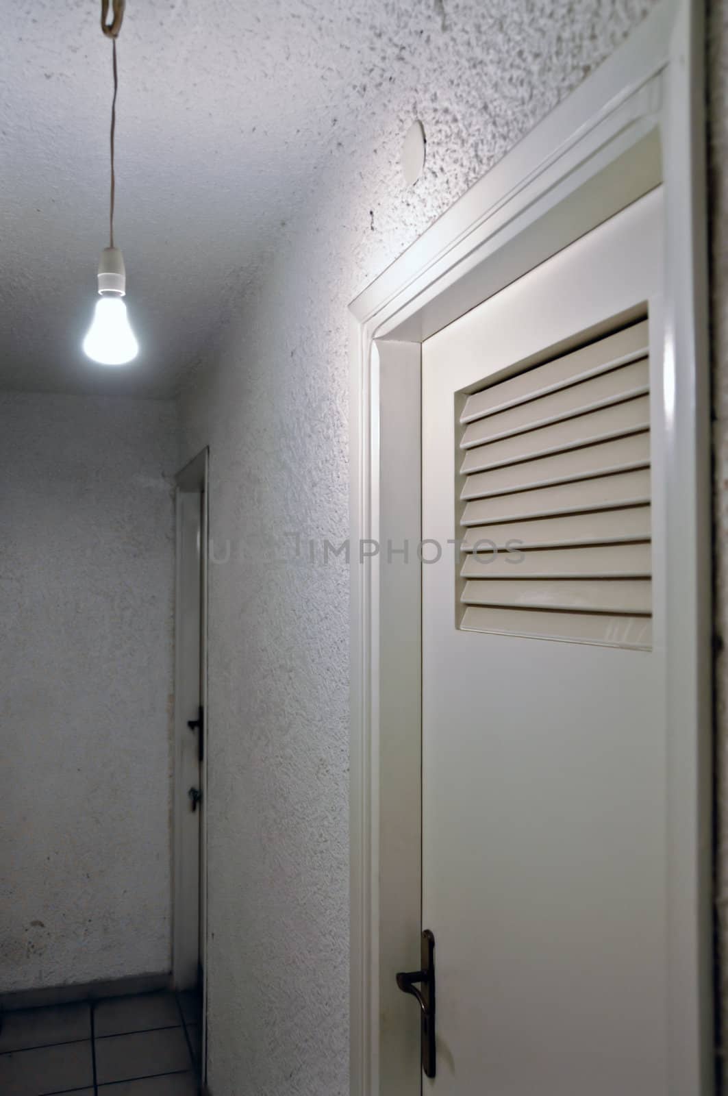 Bare light bulb and doors in underground hallway.