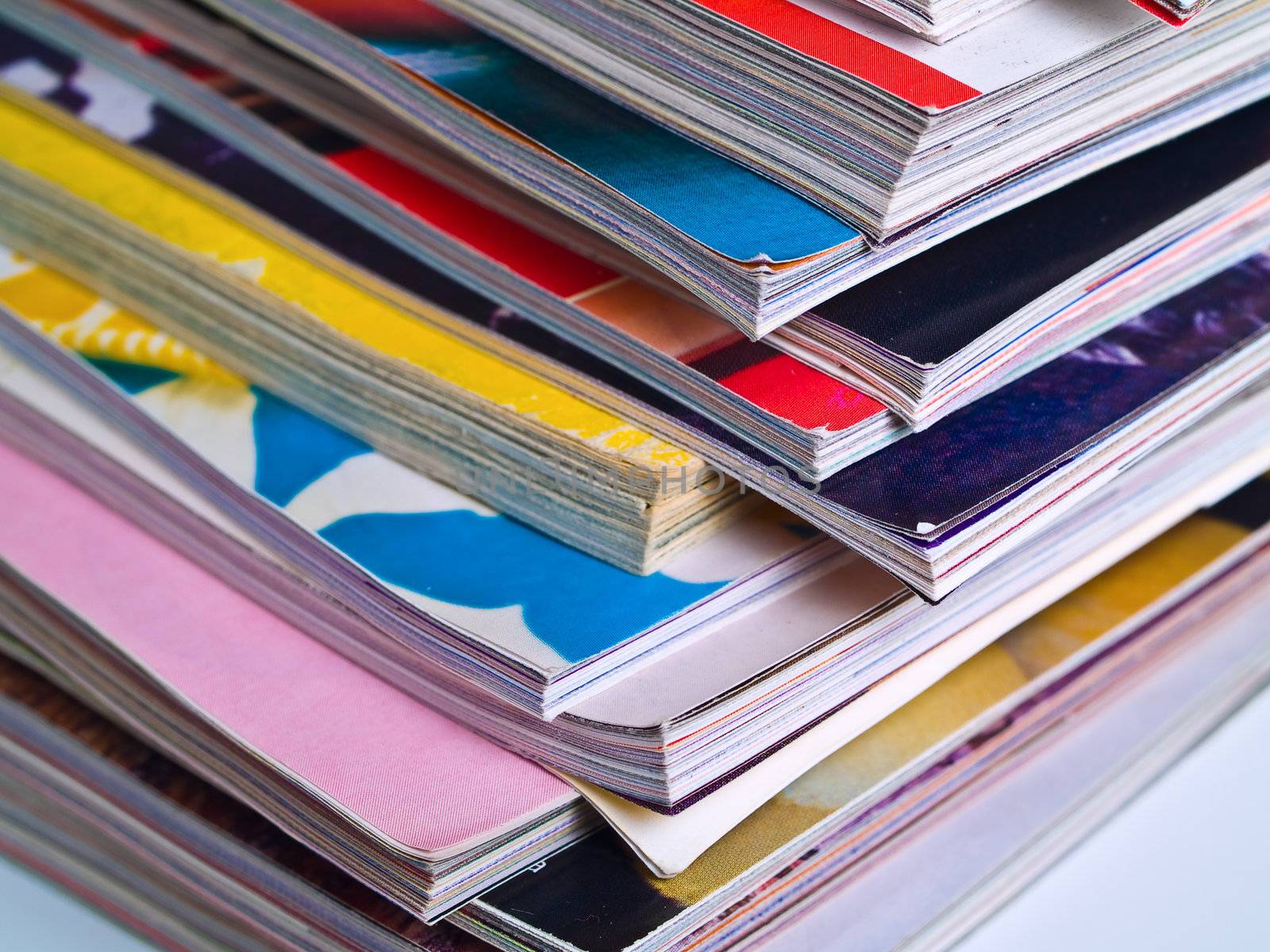 An uneven stack of magazines filling the frame from top to bottom focus on corner edge