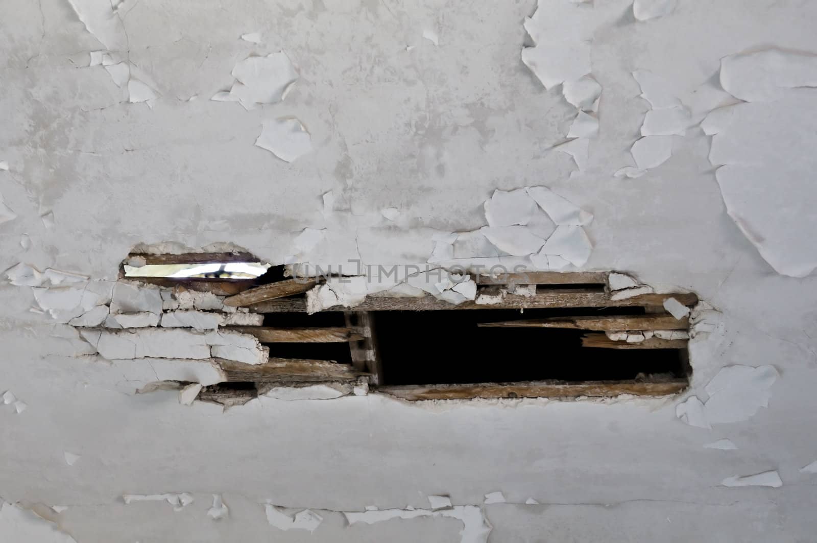 Broken wooden ceiling in abandoned house interior. Peeling paint background.