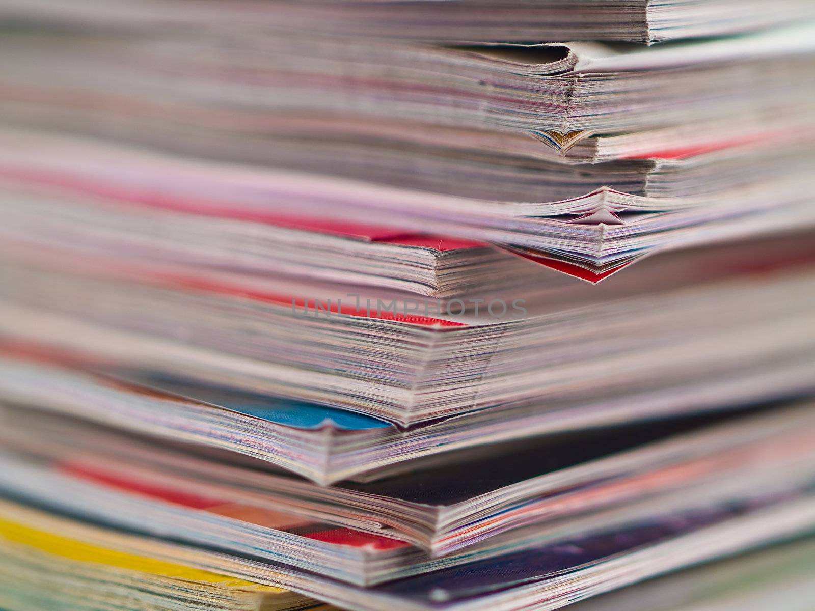 An uneven stack of magazines filling the frame from top to bottom focus on corner edge