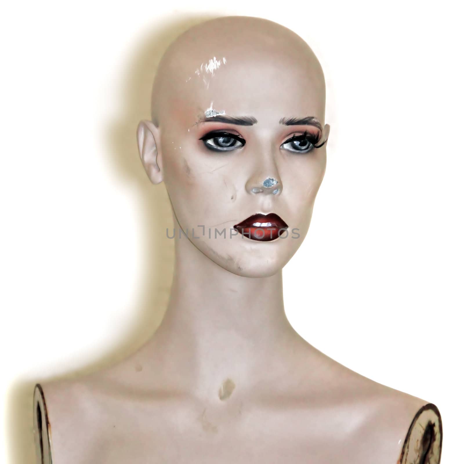 Weathered plastic mannequin doll head on white background.