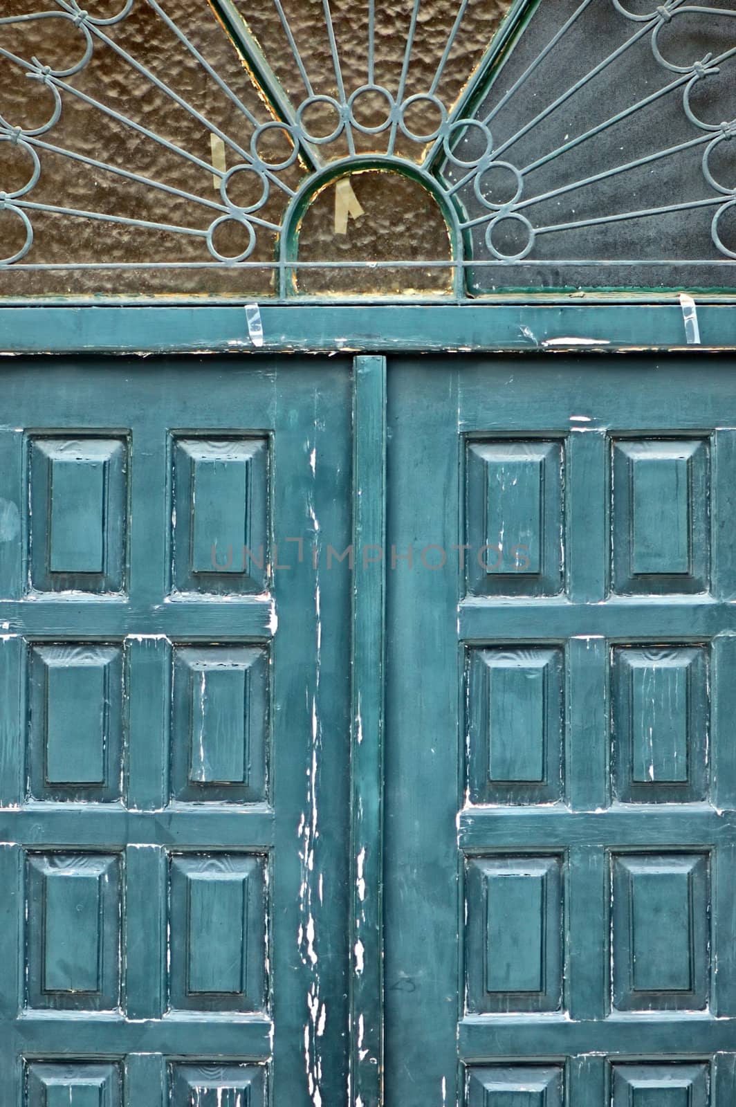 Weathered blue wooden gate with vintage ornamental sun pattern metalwork.