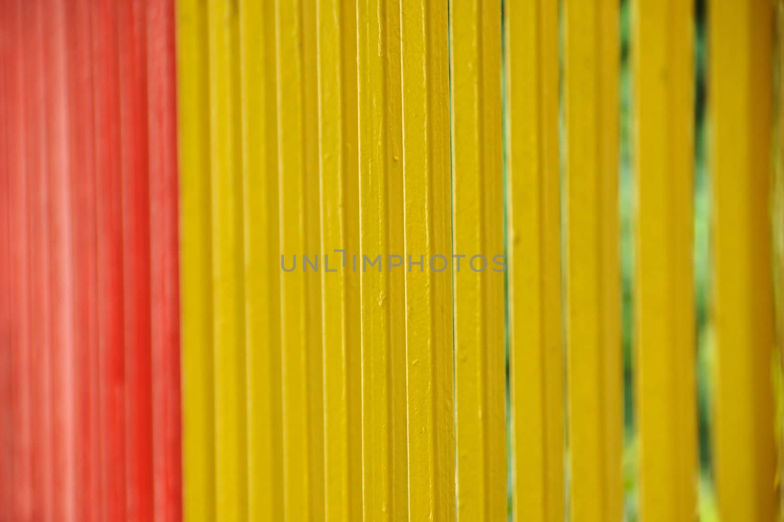 Brightly painted metal fence bars background. Selective focus.