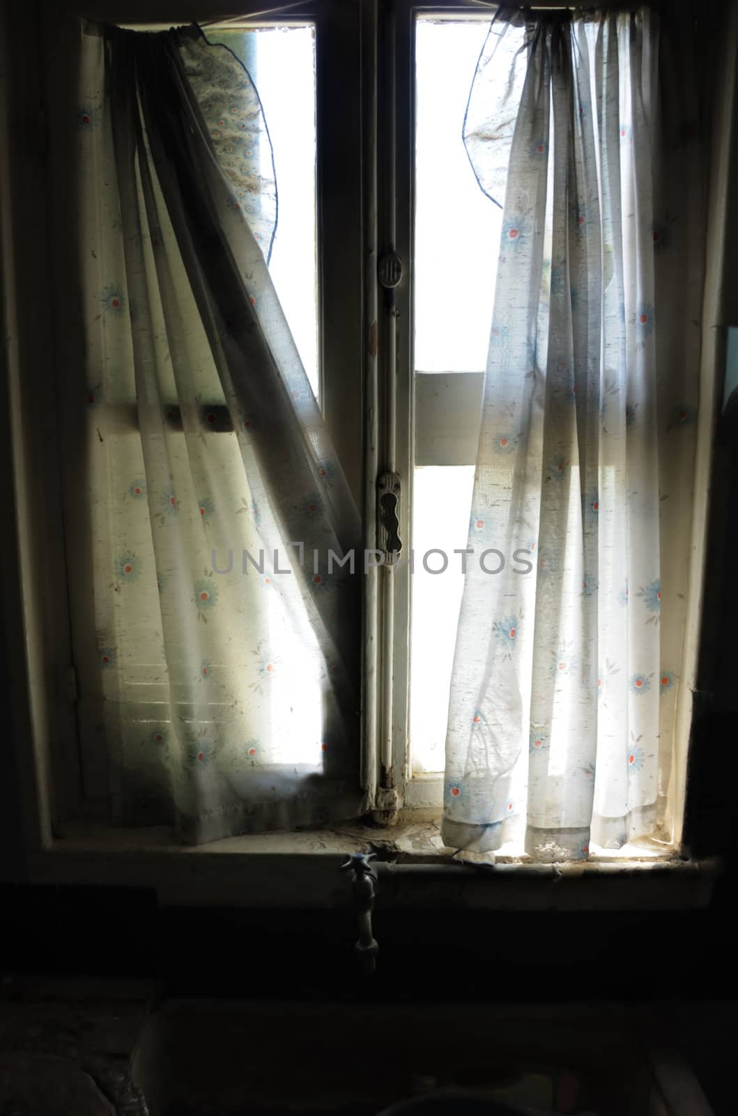 Window curtains and dirty kitchen sink in abandoned house.