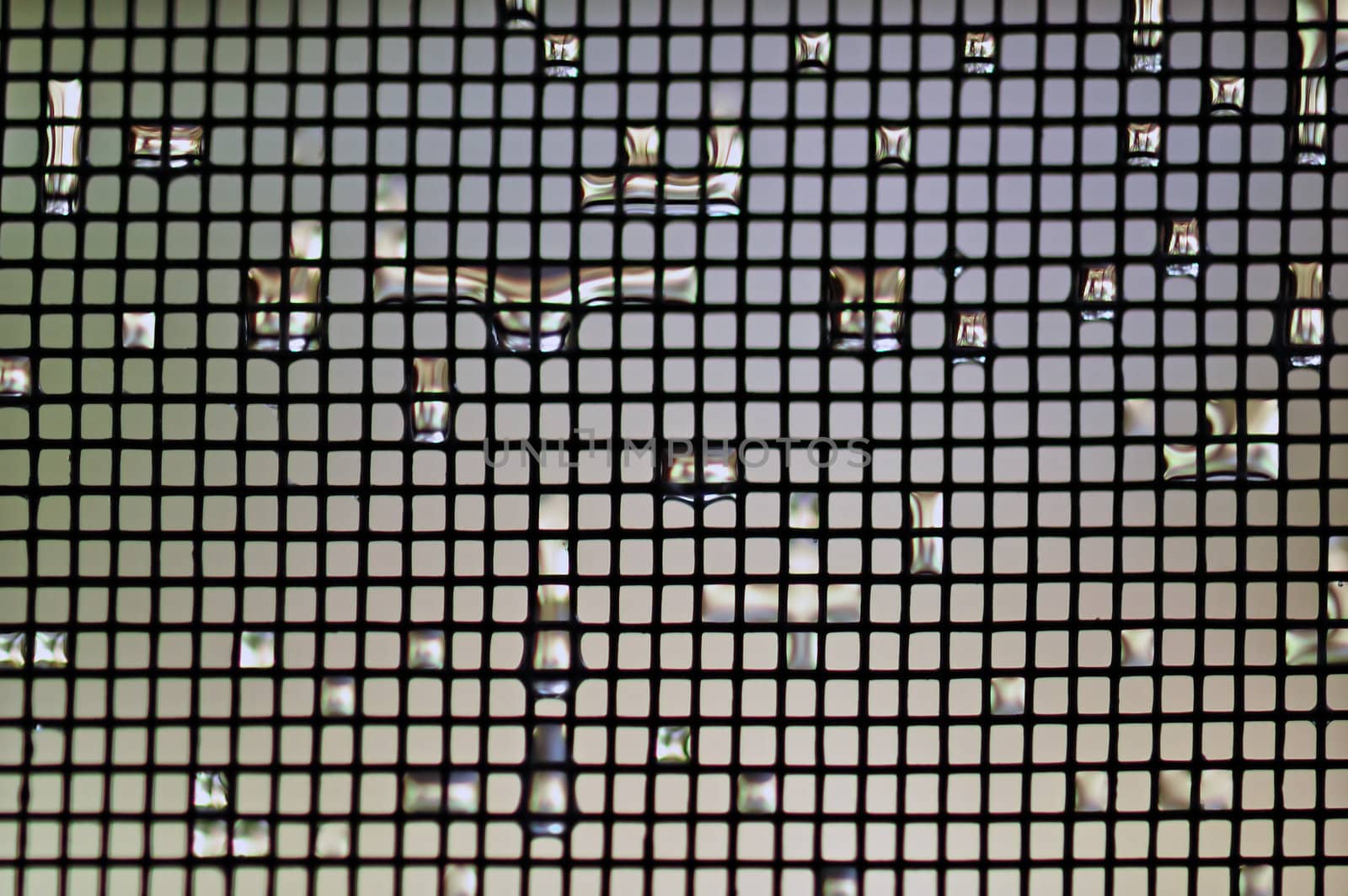 Raindrops background on wire mesh netting. Selective focus macro.
